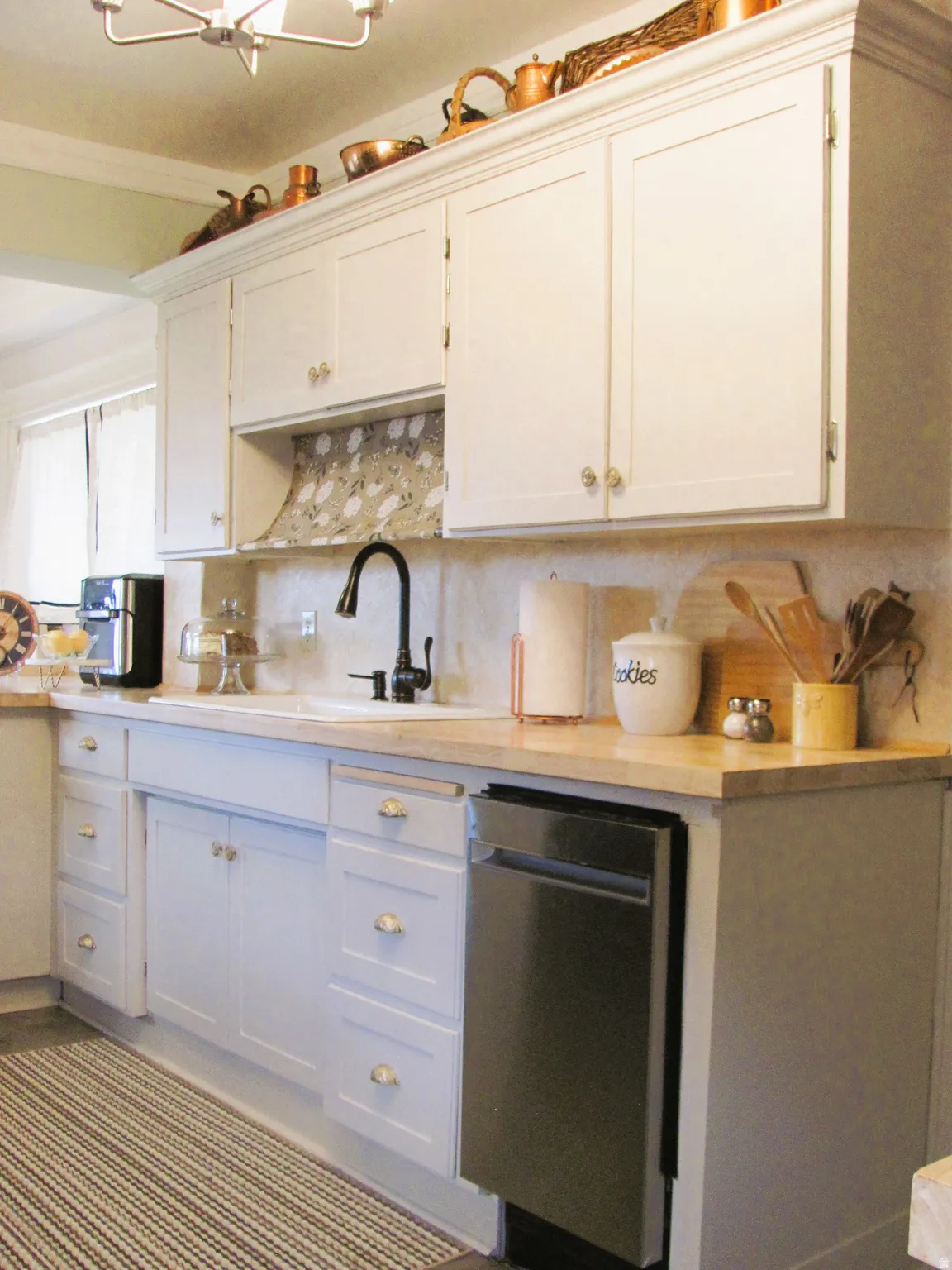 White upper and lower cabinetry featuring panel detailing and brass-finish hardware