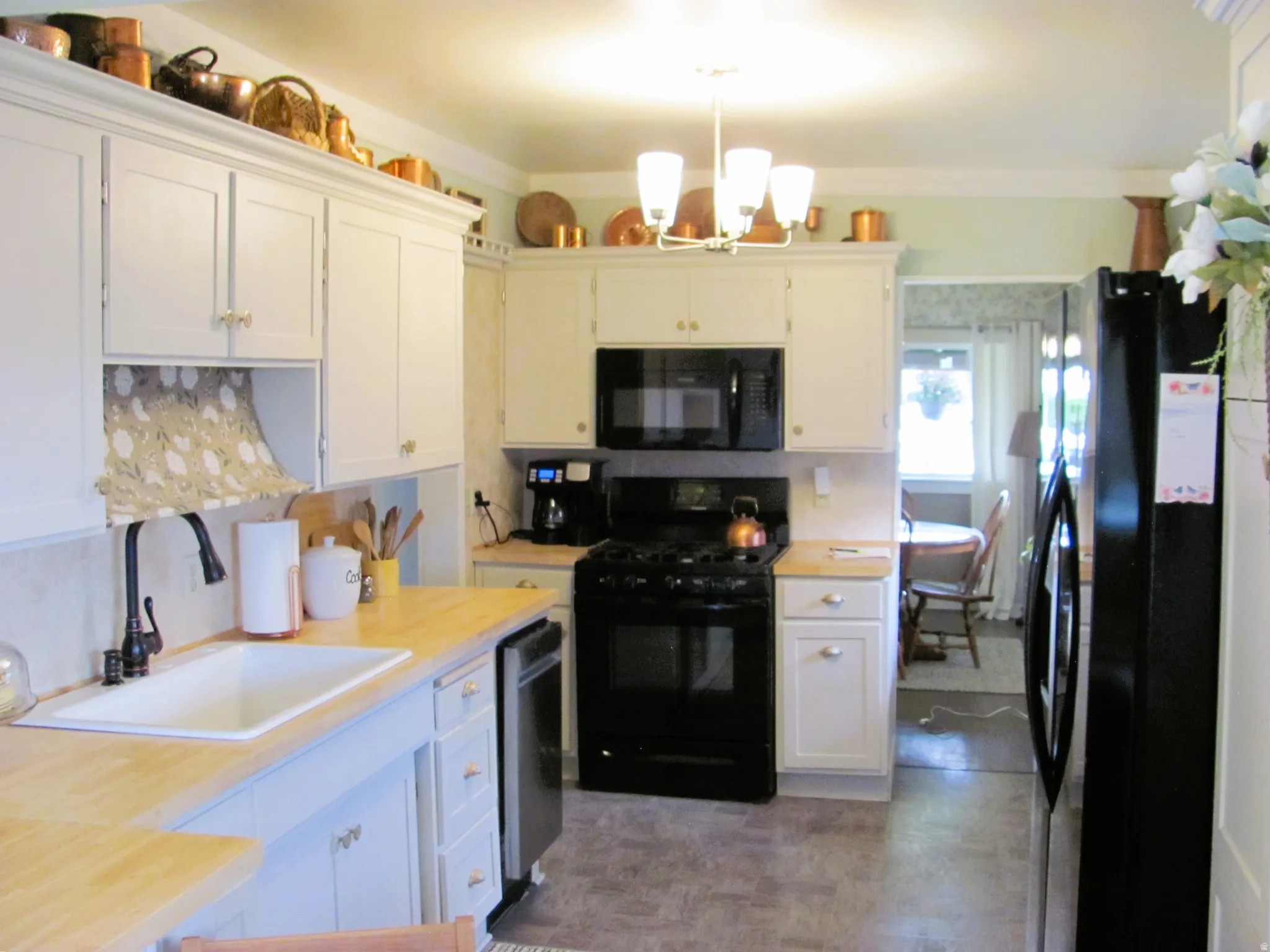 Kitchen featuring light wood-finish countertops, white cabinetry, a black gas range, and a black built-in microwave