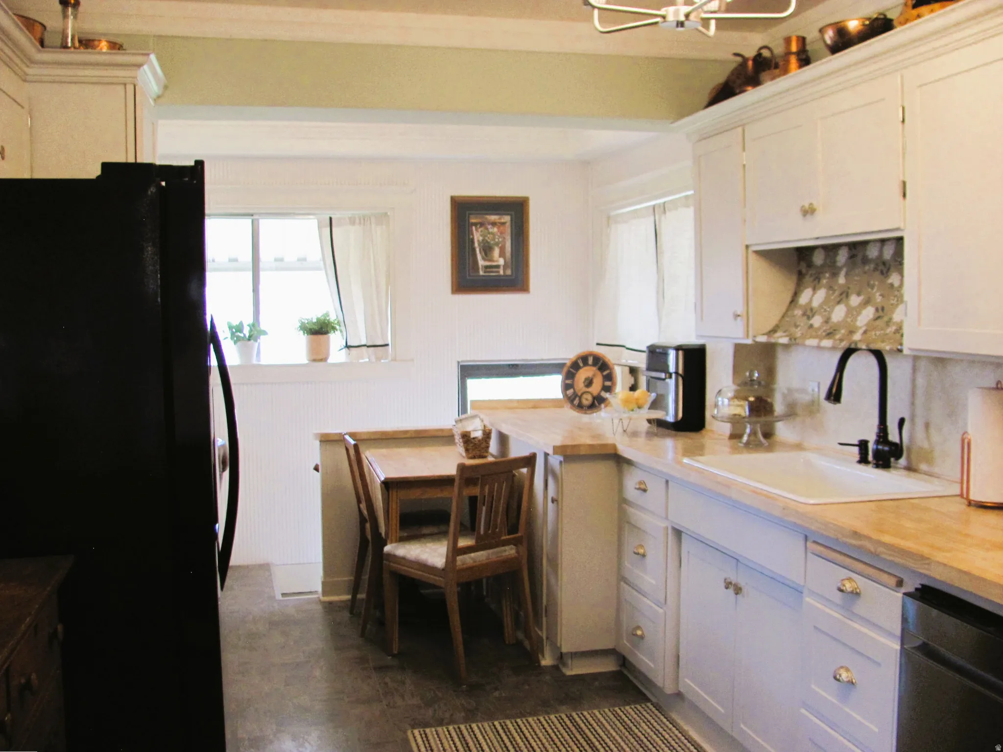 Kitchen featuring light-toned cabinetry, light wood-finish countertops, and a built-in sink with a matte black faucet