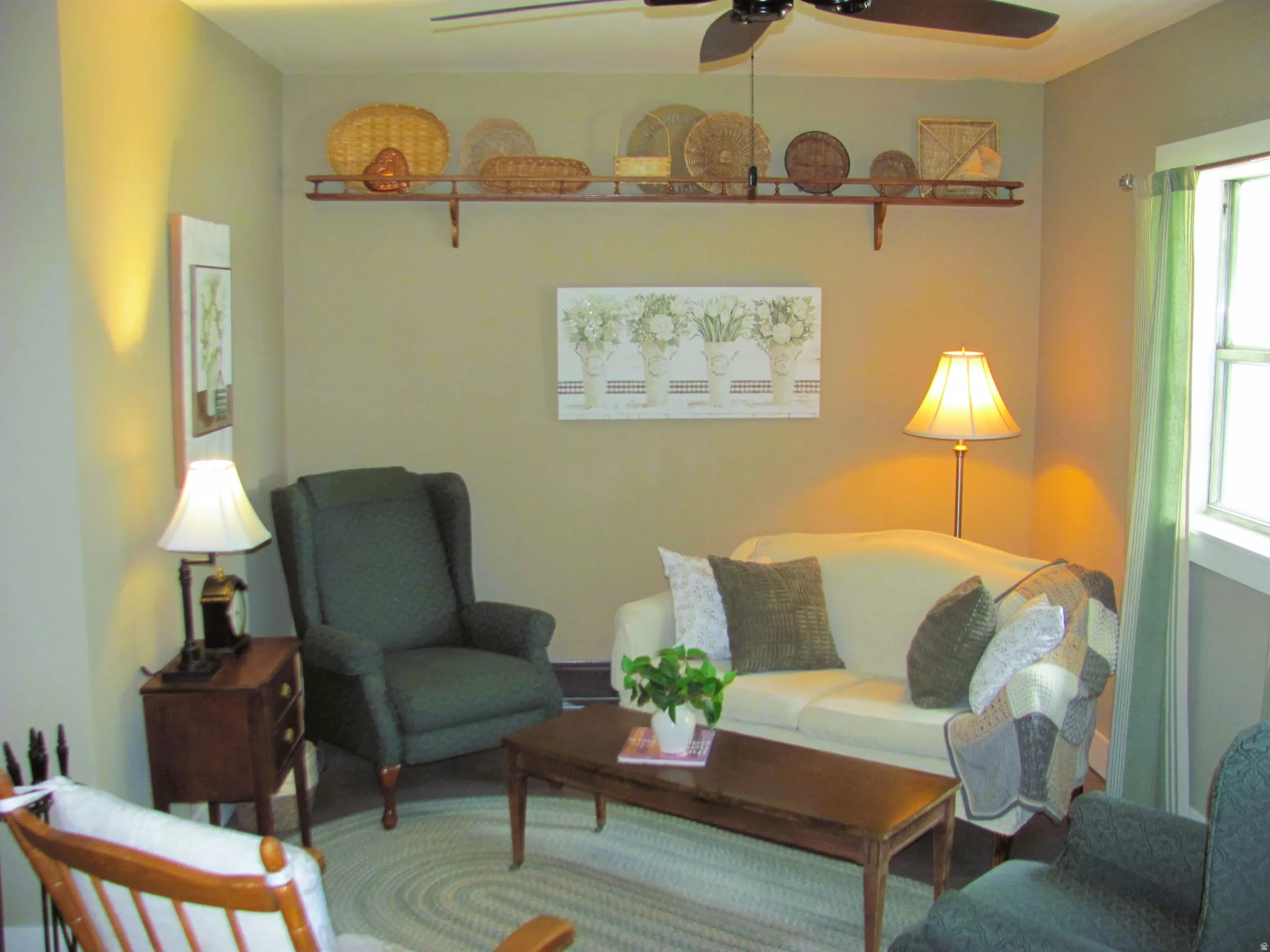 Living area with a ceiling fan, window, and wall-mounted shelving