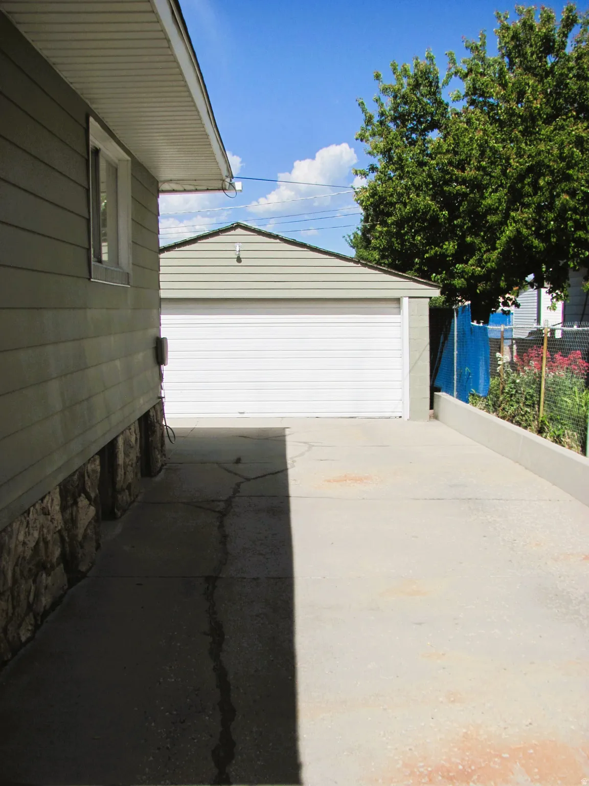 Detached garage with a white panel door, horizontal siding, and a gabled roofline