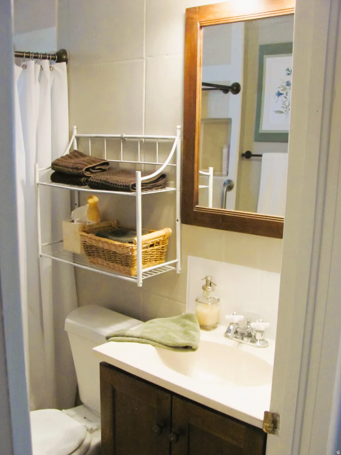 Bathroom featuring a vanity with a dark wood-finish cabinet and integrated sink, a white toilet, and light-toned wall tile
