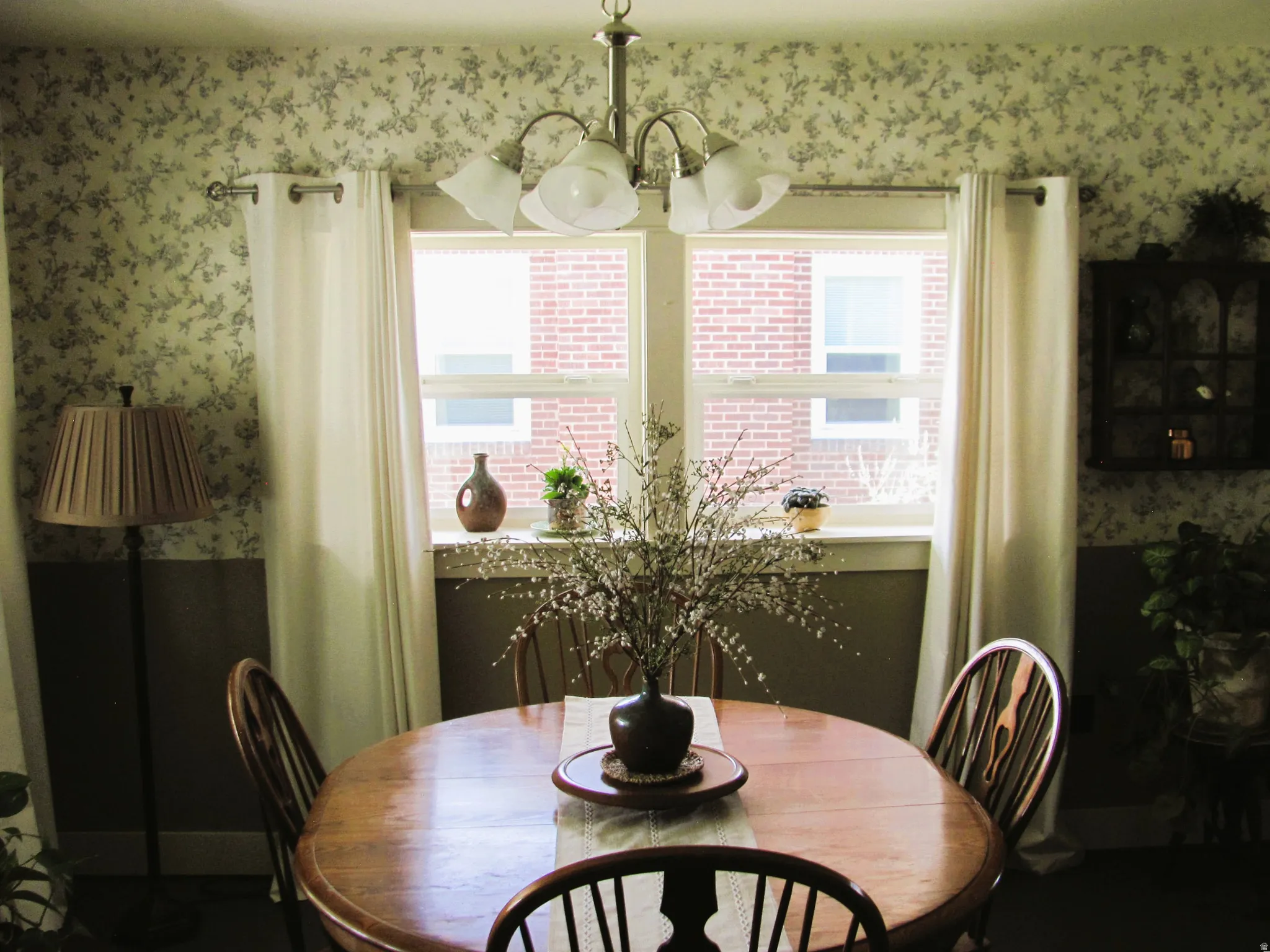 Dining space featuring a central window, floral wallpaper, and a ceiling-mounted light fixture