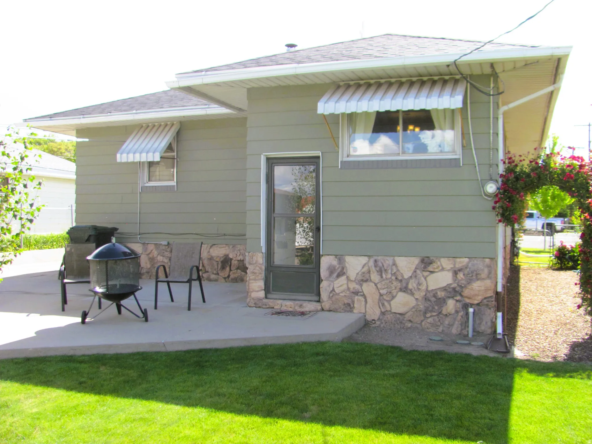 Rear exterior featuring a concrete patio, stone facade detailing, and horizontal siding