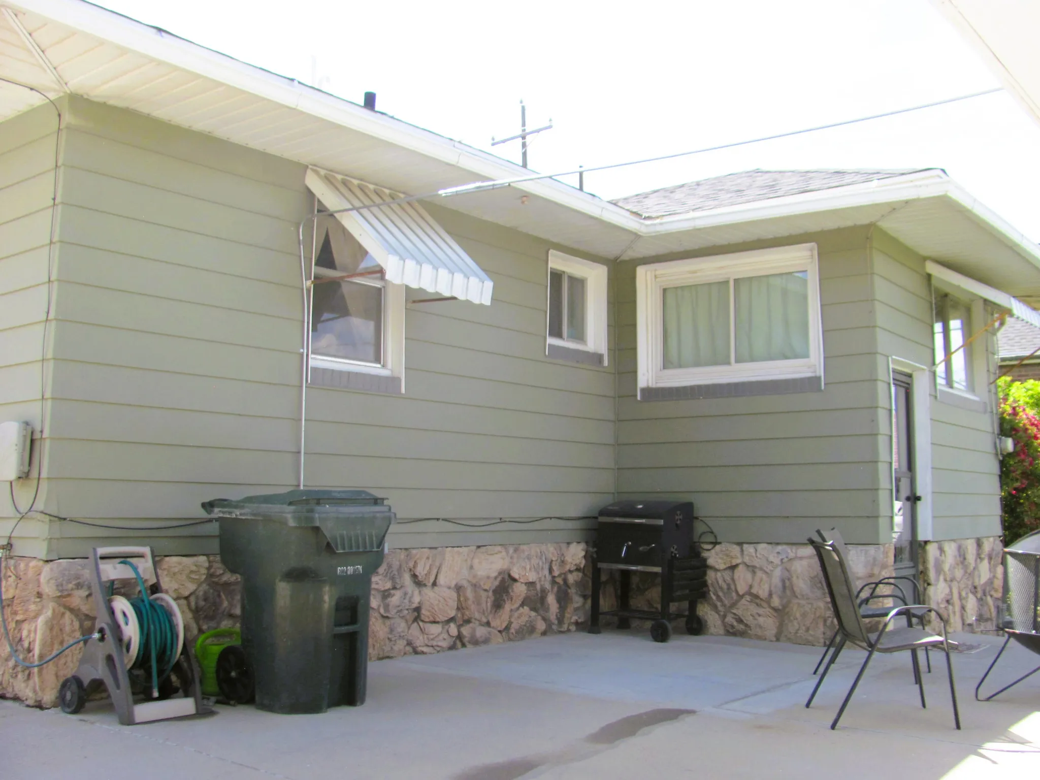 Exterior featuring light green horizontal siding and a stone-clad foundation