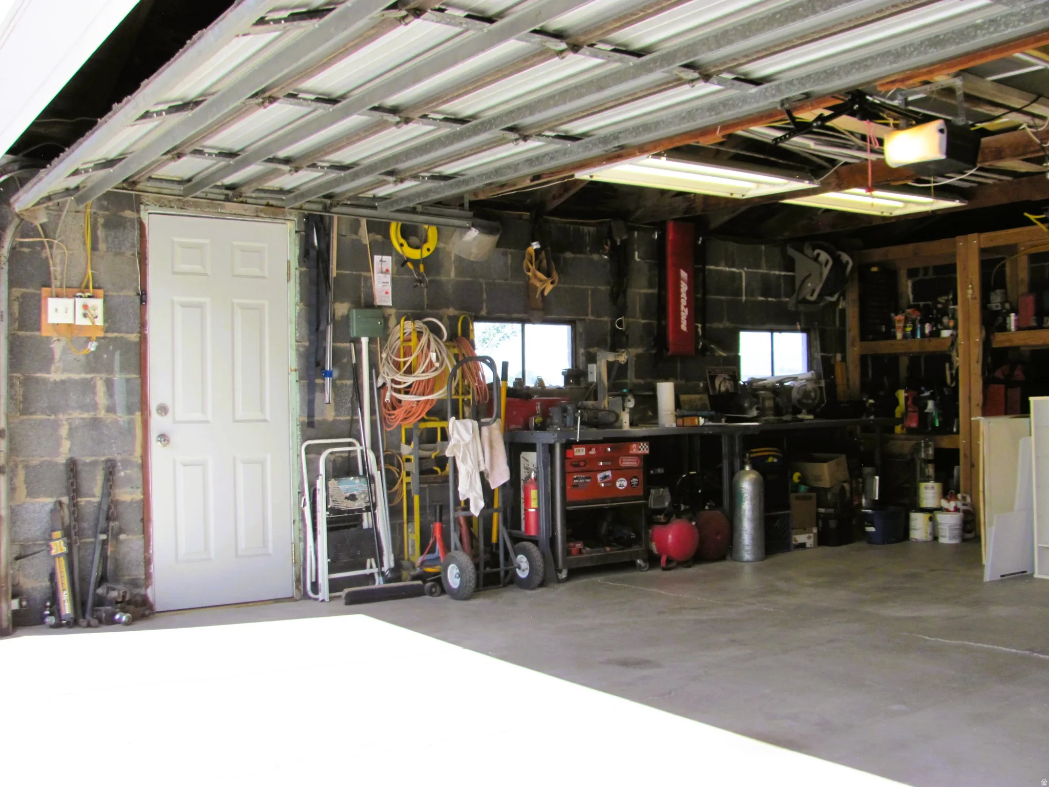 Spacious garage featuring a concrete block wall construction, an overhead garage door mechanism, and a side access door