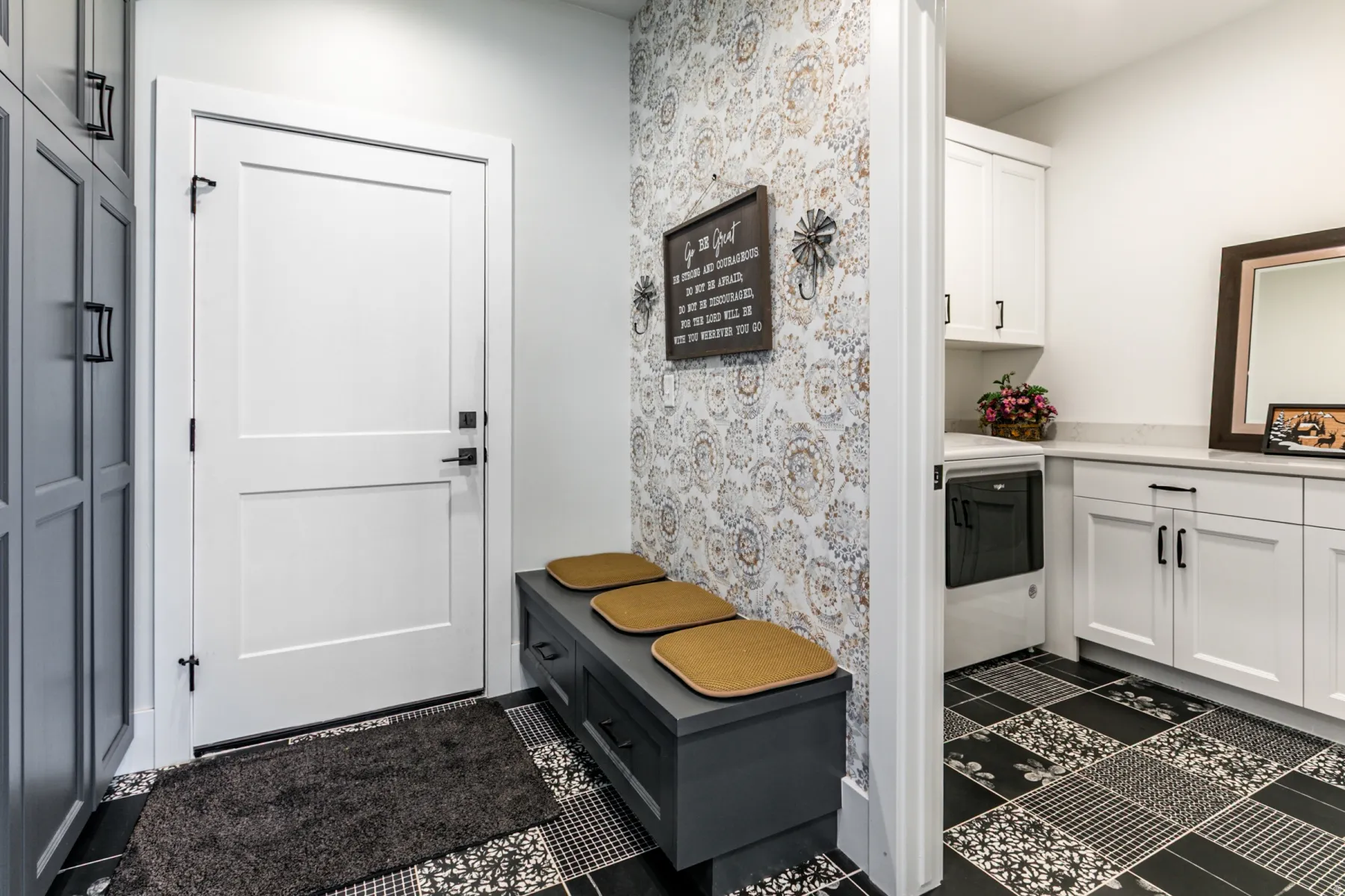 Utility space featuring patterned floor tile, built-in storage bench, and white paneled door