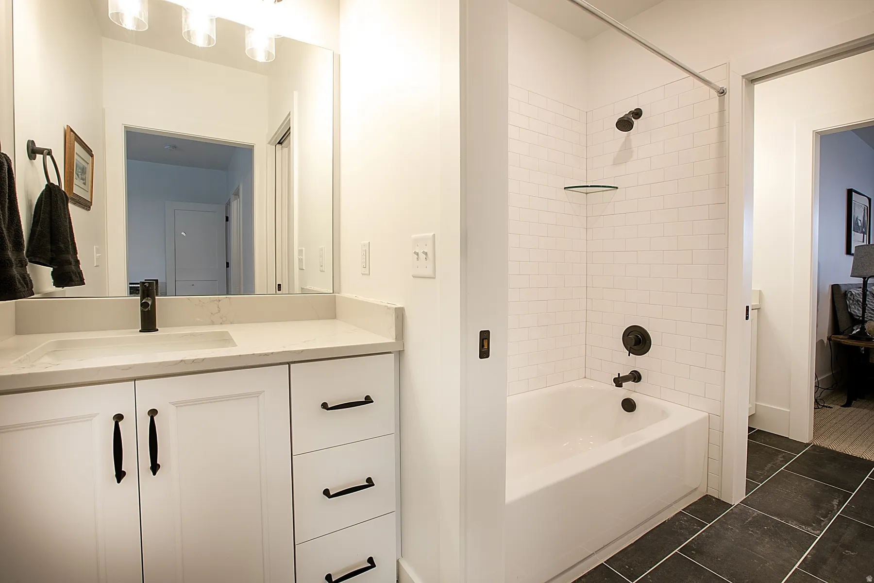 Bathroom featuring a white vanity with integrated sink, a large mirror, and overhead lighting