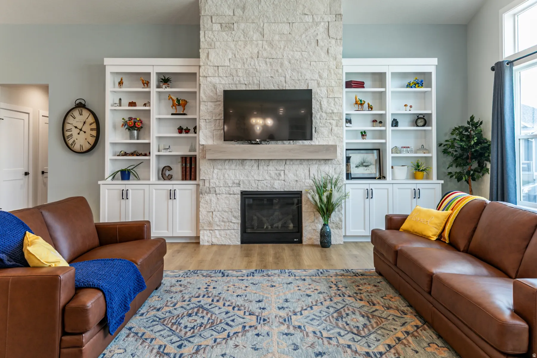 Stacked stone fireplace with a wood-finish mantle, flanked by built-in white cabinetry and shelving