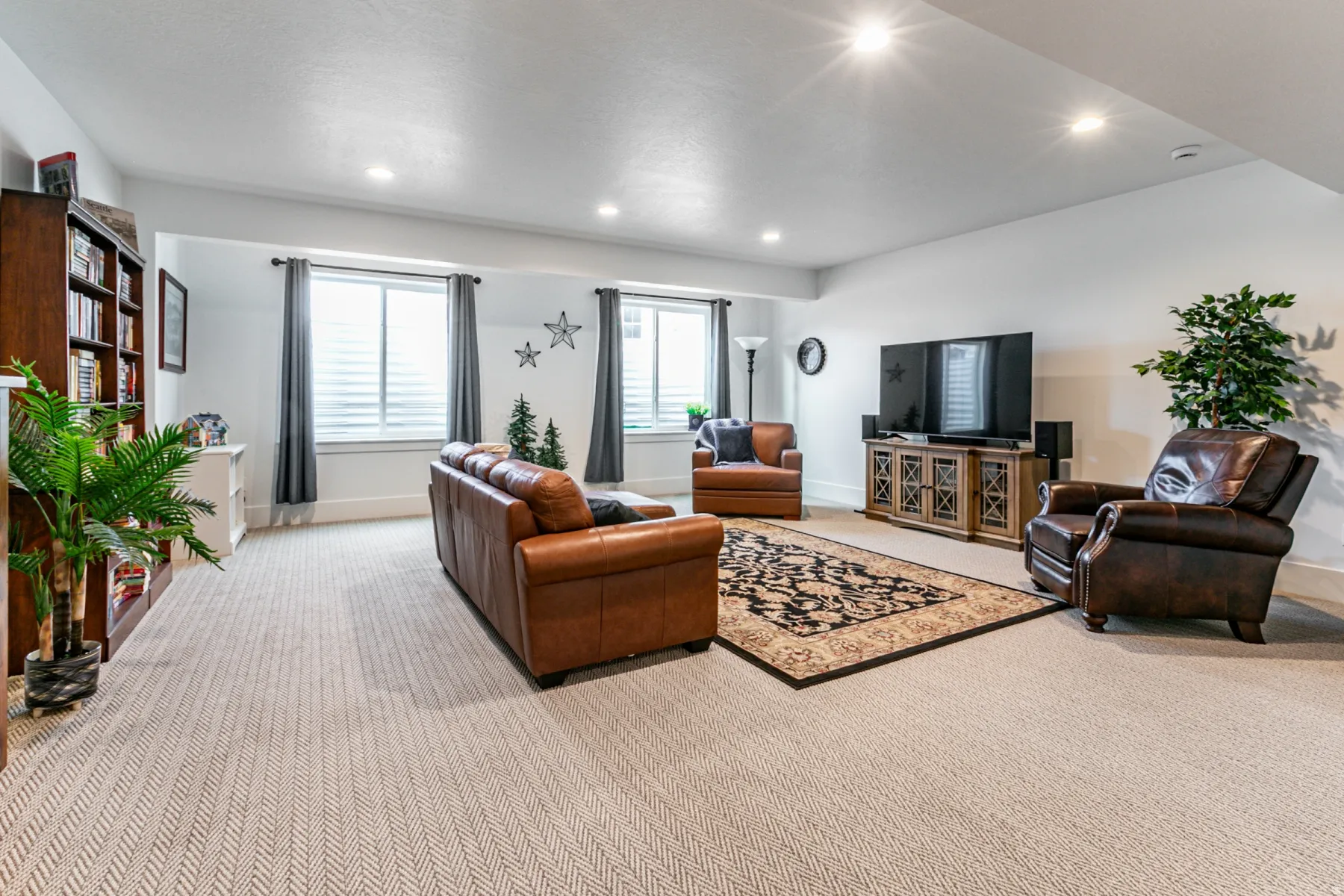 Spacious living area featuring recessed lighting, light-toned patterned carpeting, and dual windows with privacy blinds