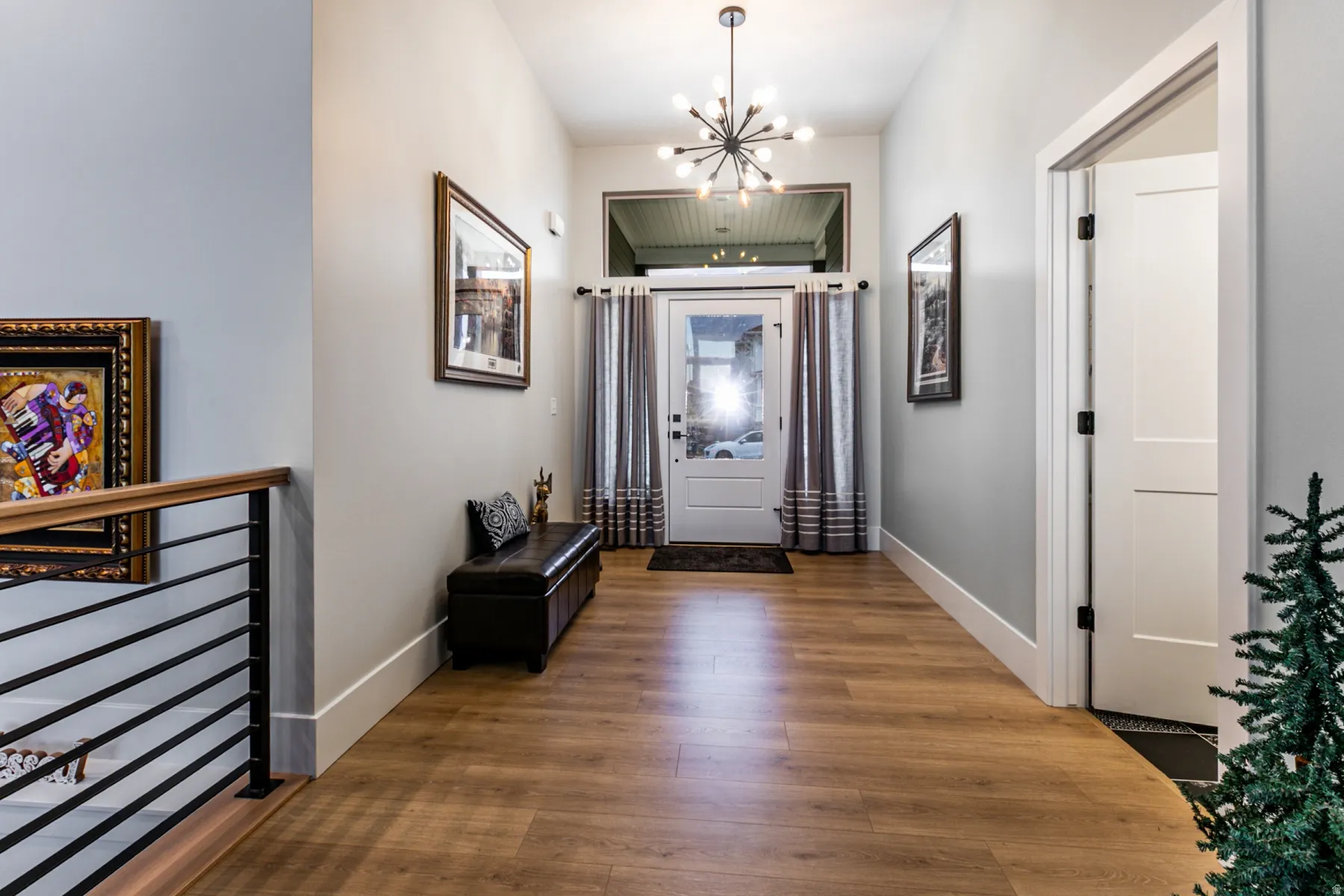 Entryway featuring wood-finish flooring, a modern sputnik chandelier, and a white paneled door
