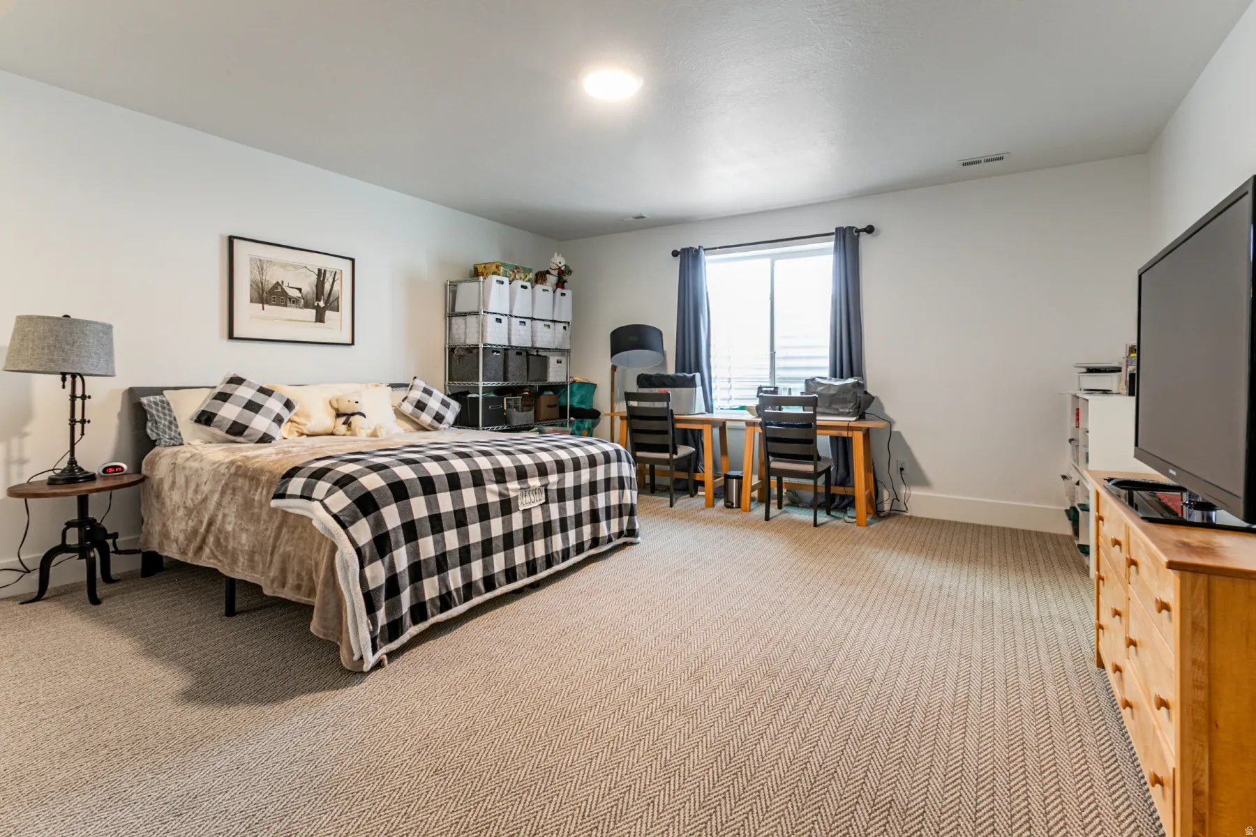 Spacious room featuring neutral carpeting, white walls, a recessed ceiling light, a window with blinds and drapes, and white baseboards