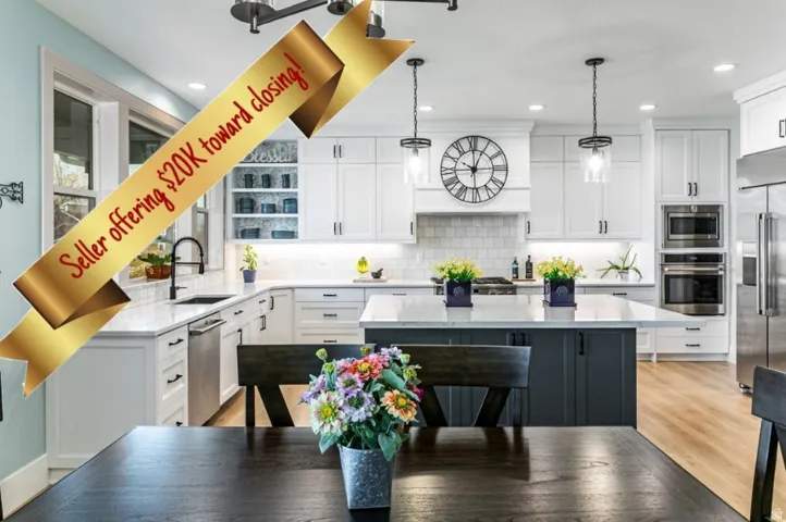Gourmet kitchen featuring white shaker cabinetry, an oversized island with contrasting base cabinetry, stainless steel appliances, pendant lighting, and wood-finish flooring