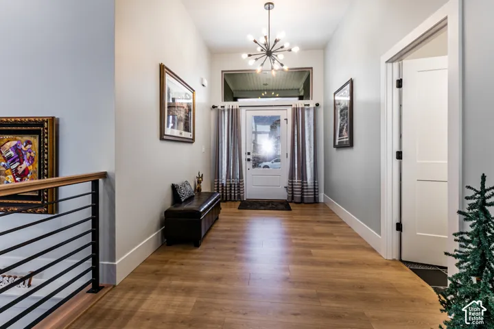 Entryway featuring wood-finish flooring, a modern sputnik chandelier, and a white paneled door