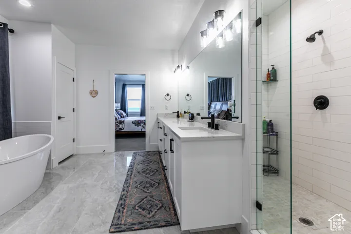 Contemporary bathroom featuring a freestanding tub, dual vanity with undermount sinks and black fixtures, and a glass-enclosed shower with subway tile surround