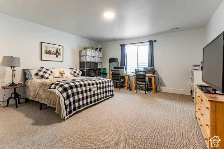 Spacious room featuring neutral carpeting, white walls, a recessed ceiling light, a window with blinds and drapes, and white baseboards