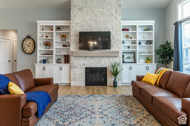 Stacked stone fireplace with a wood-finish mantle, flanked by built-in white cabinetry and shelving