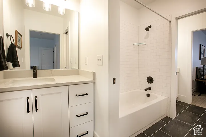 Bathroom featuring a white vanity with integrated sink, a large mirror, and overhead lighting