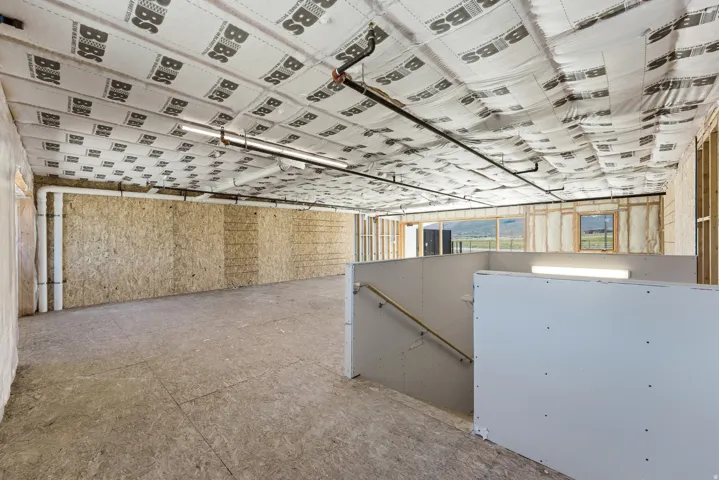 Spacious unfinished basement with exposed ceiling insulation, visible plumbing, and electrical lines