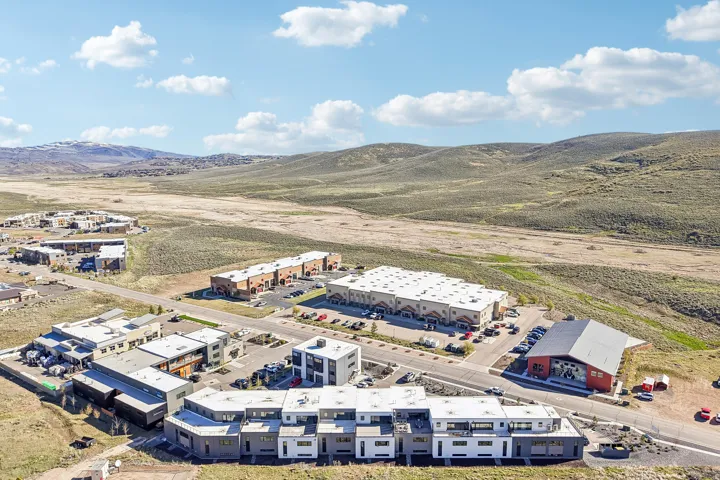 Aerial perspective showcasing a residential and commercial development situated amidst undulating natural terrain