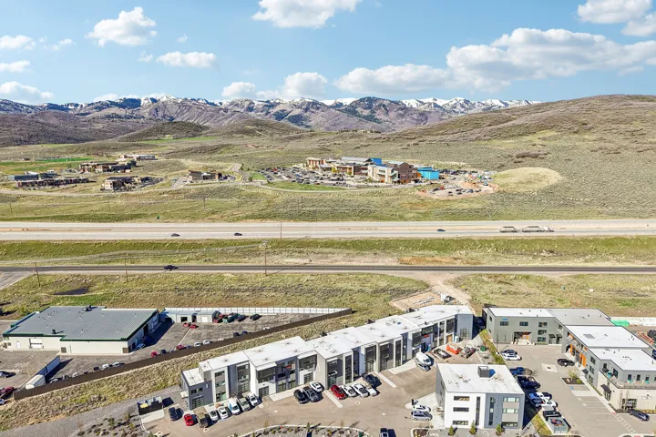 Aerial perspective showcasing multi-story modern buildings with flat roofs, multiple parking areas, and surrounding natural landscapes