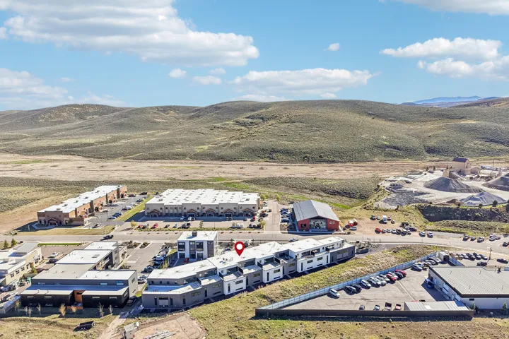 Modern multifamily residential buildings with distinct architectural designs, surrounded by expansive undeveloped hills