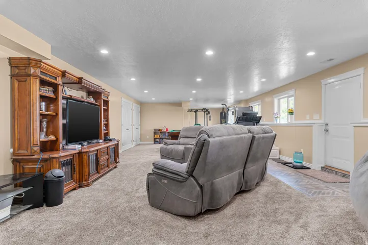 Spacious room featuring neutral carpeting, recessed lighting, and a built-in wood entertainment center