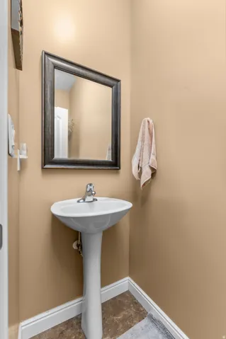 Pedestal sink with chrome faucet, framed mirror, and warm beige wall tones