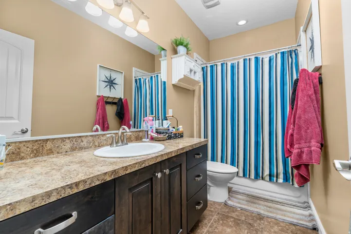Bathroom featuring a dark wood-finish vanity with a laminate countertop, an undermount sink, and a chrome-finish faucet