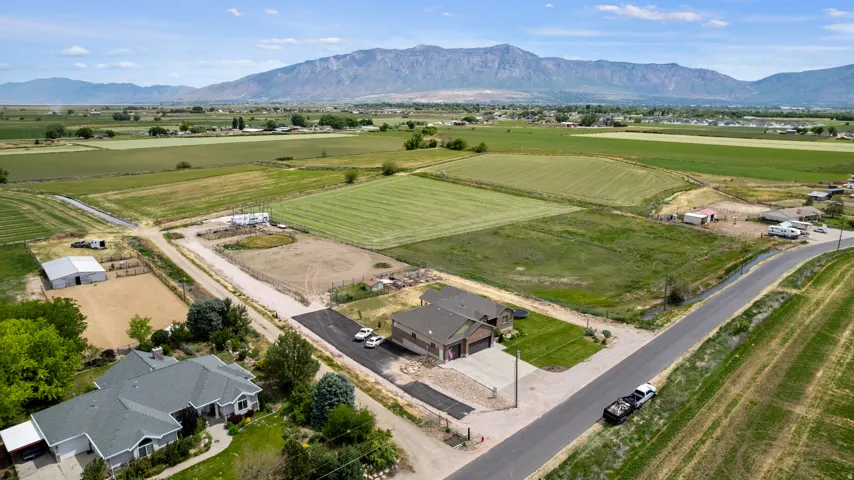 Expansive rural property featuring a large barn, a fenced equestrian arena, and an open field