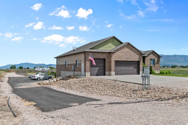 Brick exterior with a multi-car garage, concrete driveway, and a paved approach