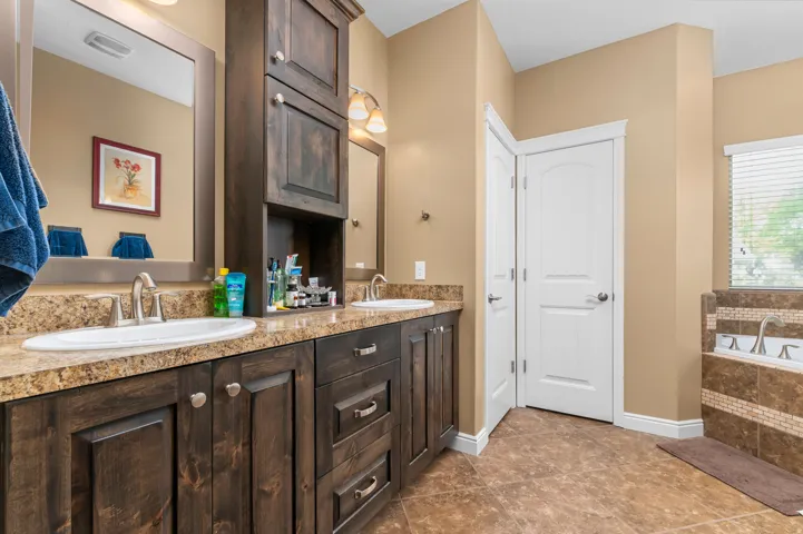 Dual vanity with dark wood-finish cabinetry, speckled countertops, and undermount sinks