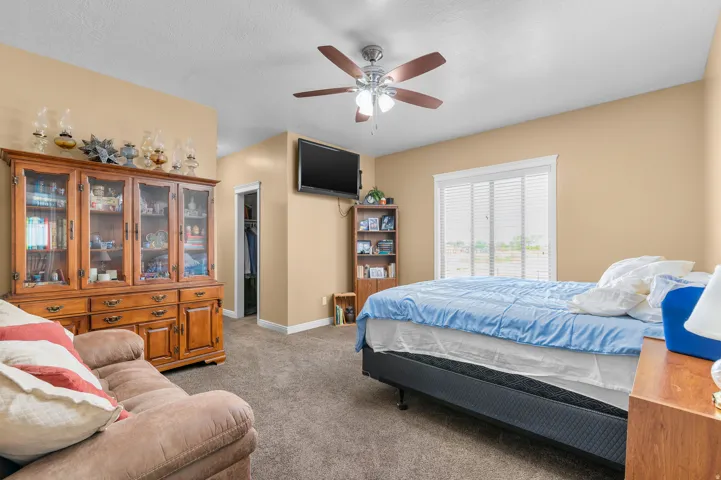 Spacious room featuring carpeting, neutral wall tones, a ceiling fan with integrated lighting, and a window with blinds