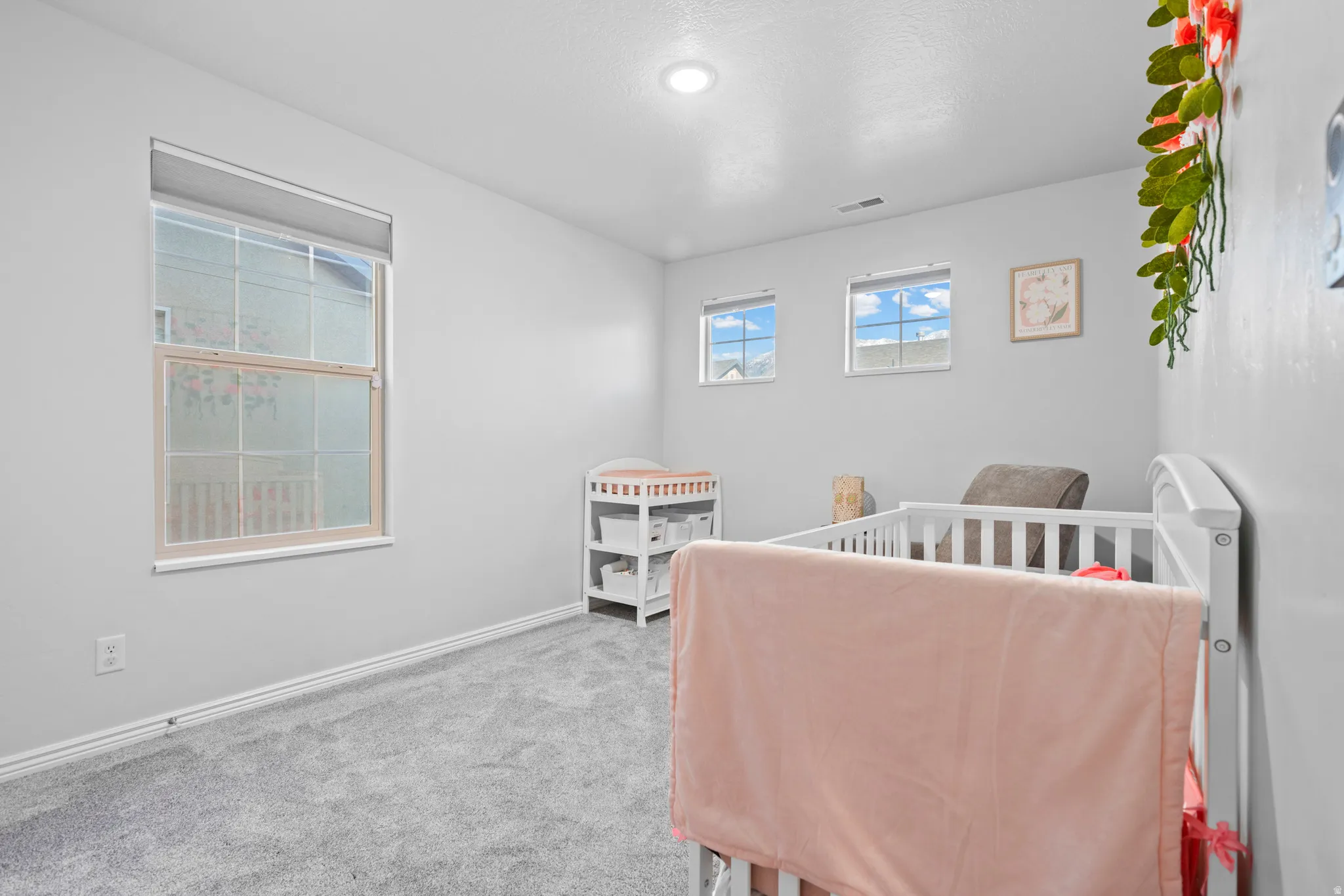 Spacious room featuring light gray wall paint, gray carpet flooring, and white baseboards