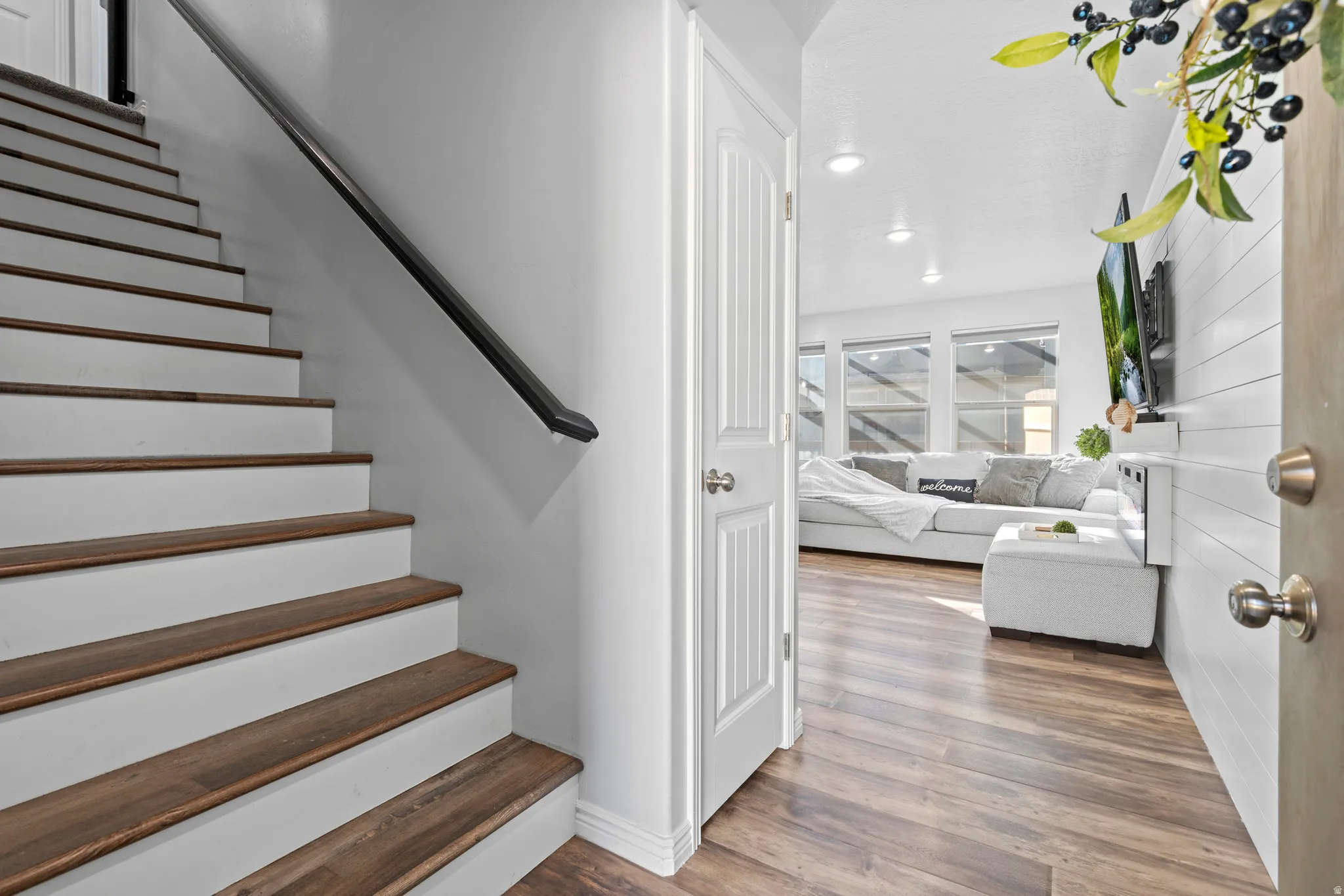 Wood-finish flooring throughout, bright white walls, recessed lighting, white shiplap wall accent, and multiple windows providing natural illumination