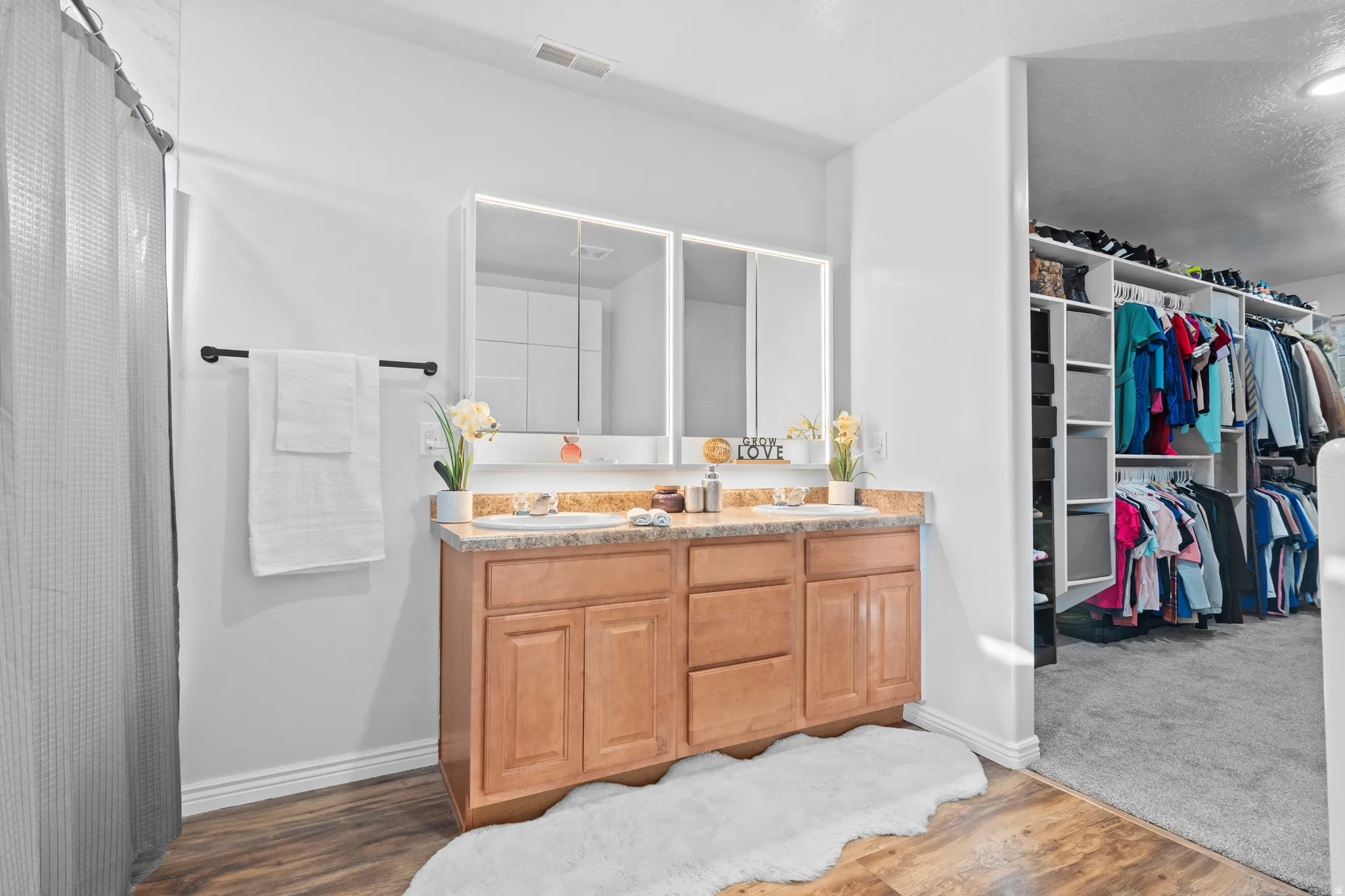 Dual vanity with wood-finish cabinetry, under-mount sinks, and a stone-finish countertop
