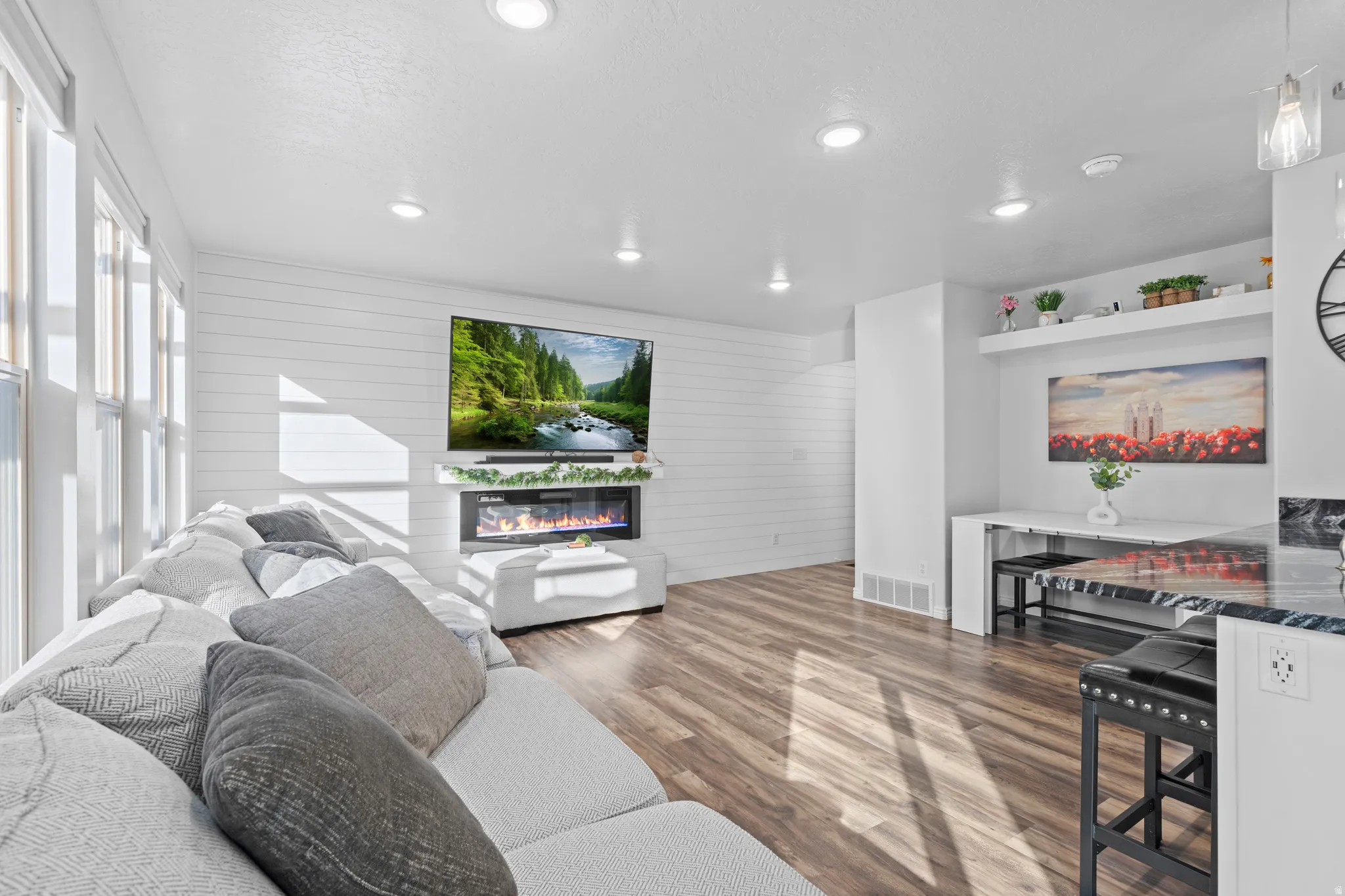 Open-concept living area featuring wood-finish flooring, recessed lighting, and a shiplap accent wall