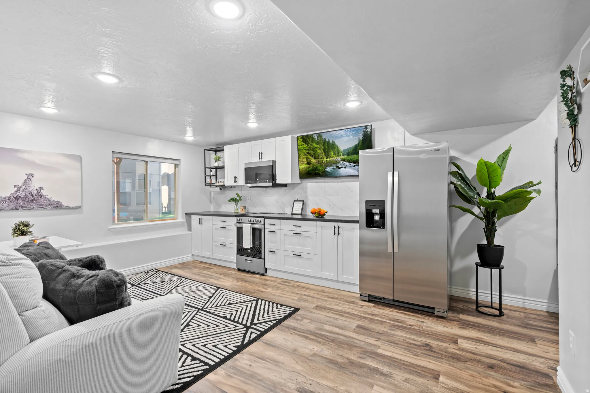 Open-concept living space featuring wood-finish flooring, recessed lighting, and a window for natural light