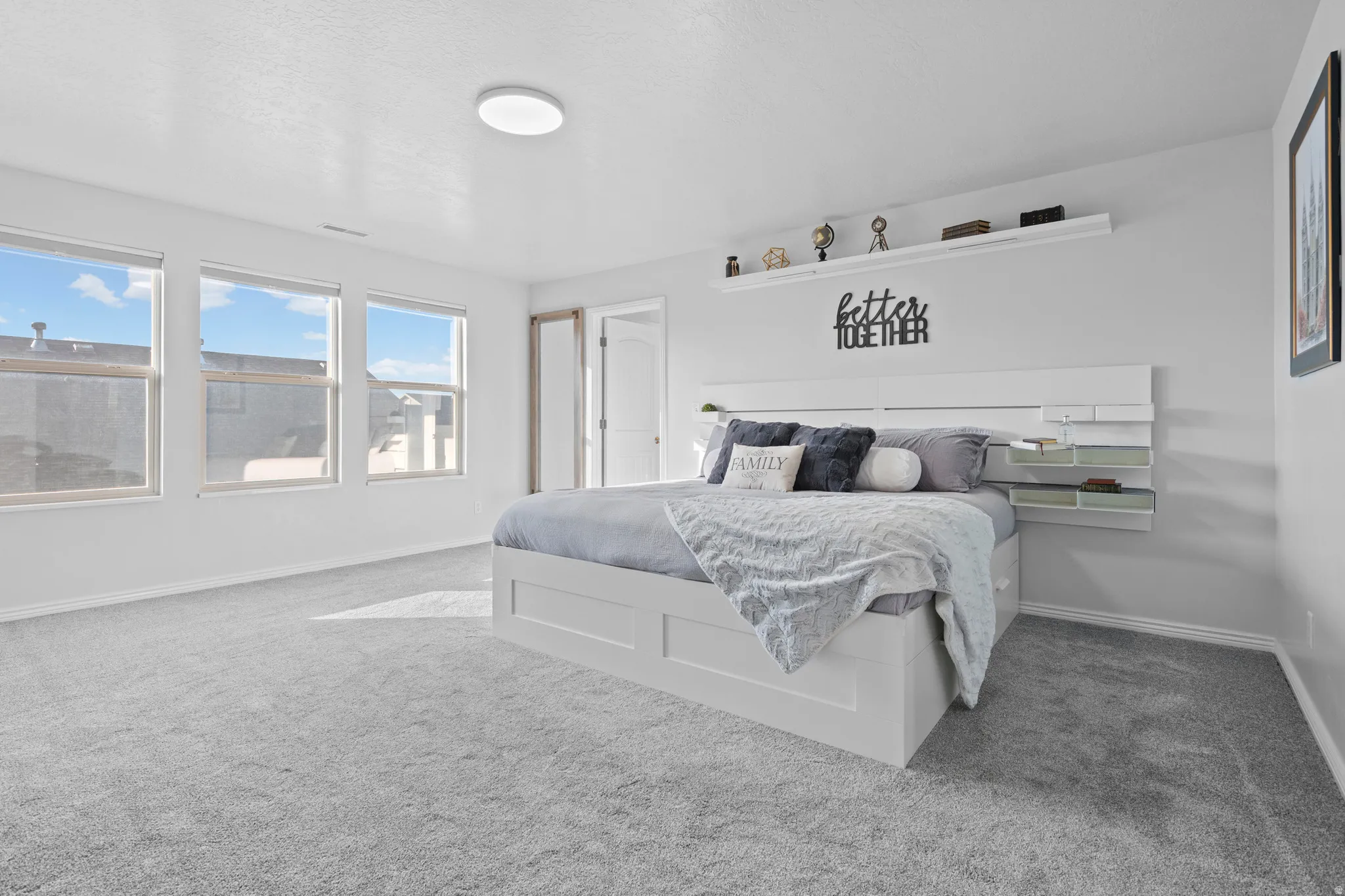 Spacious room featuring light gray carpeting and three large windows