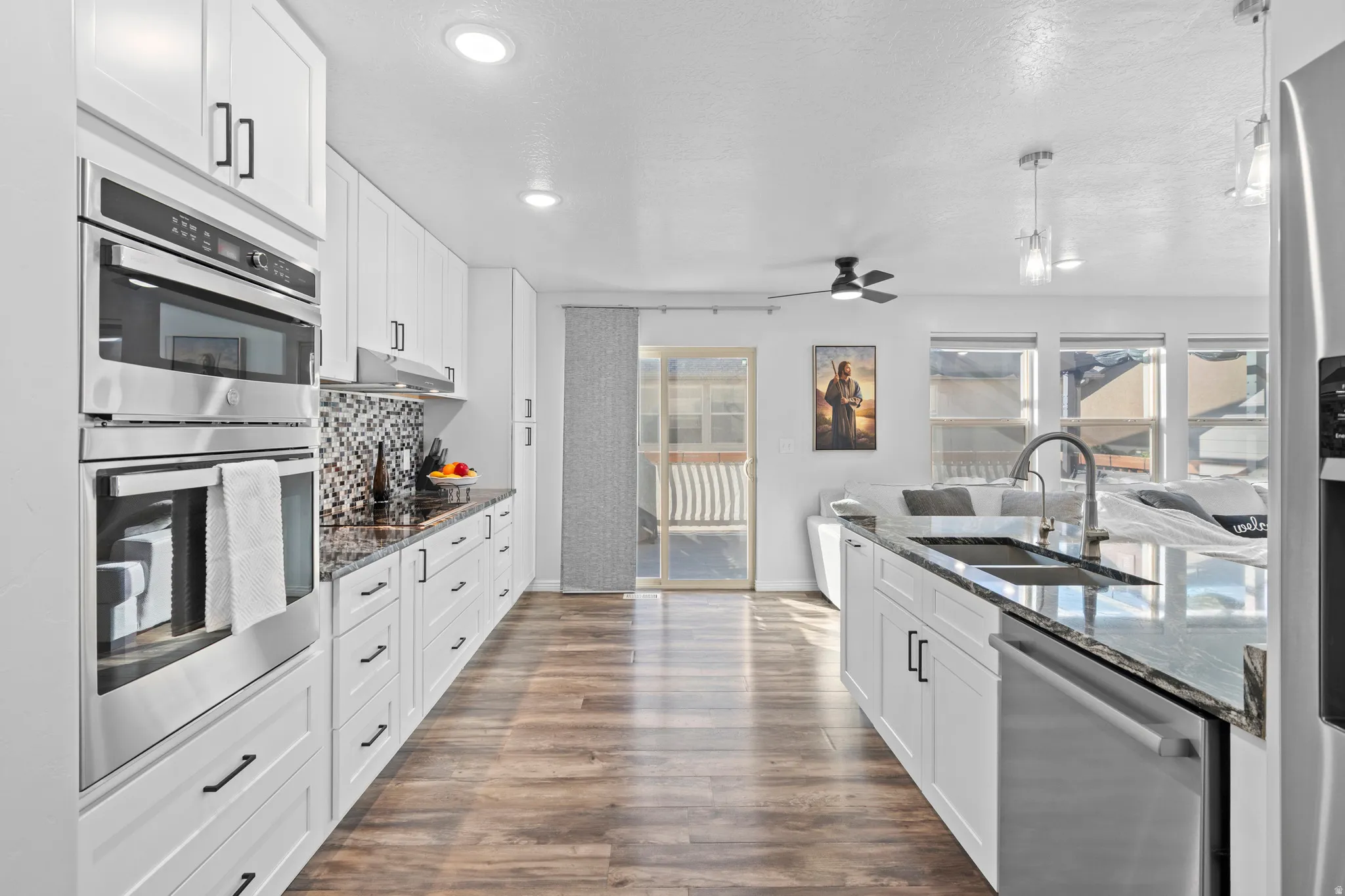 Modern kitchen featuring wood-finish flooring, white cabinetry, and stainless steel appliances