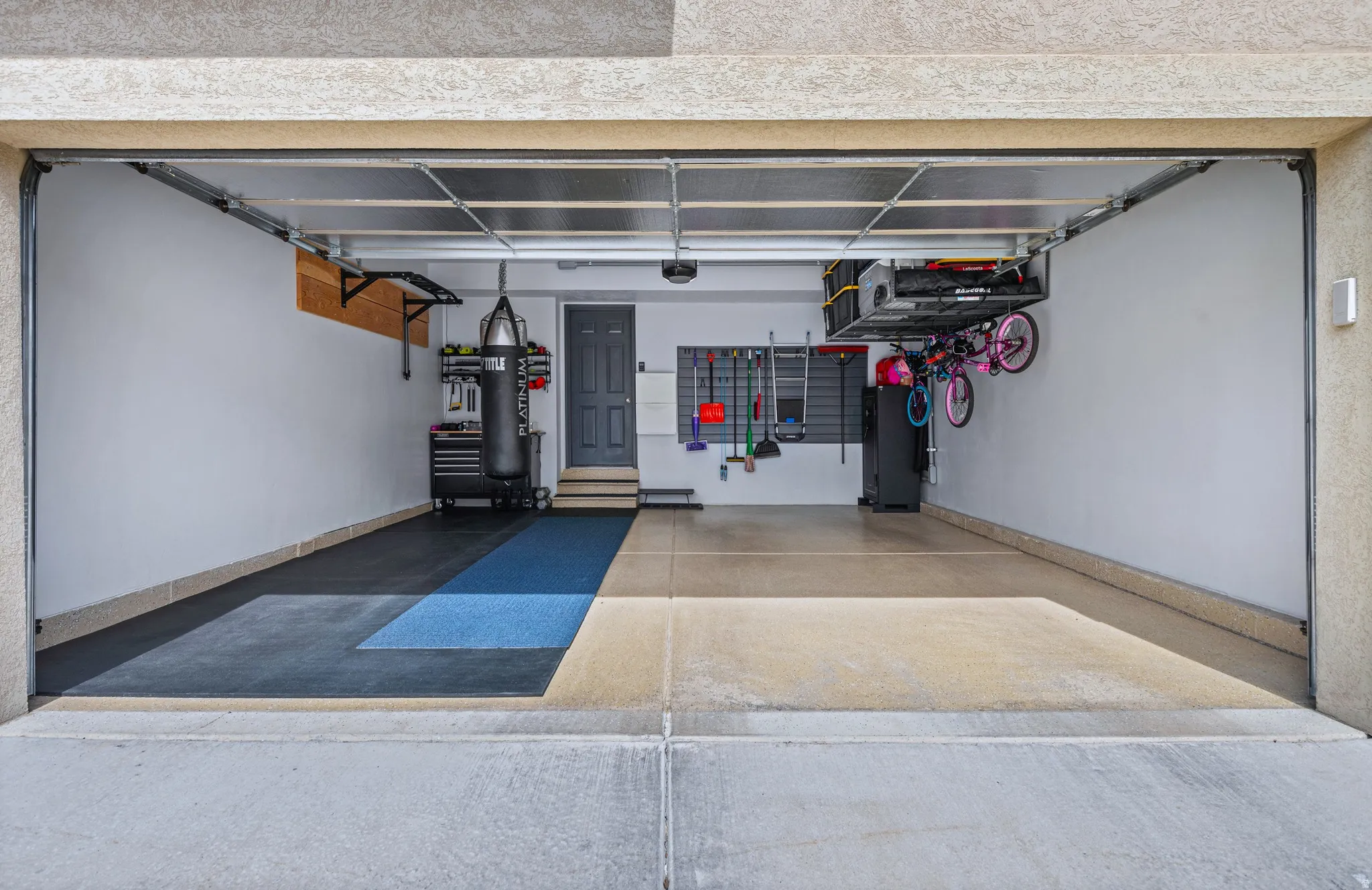 Spacious garage featuring a concrete floor at the entrance, transitioning to a combination of light-colored and dark-colored floor tiles