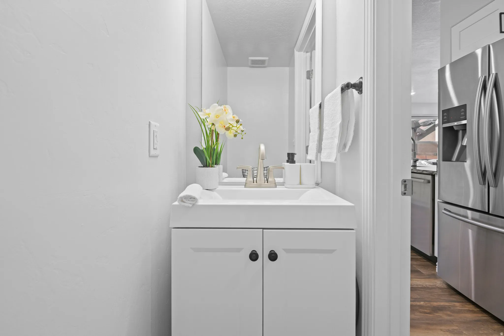 Bathroom vanity featuring an integrated sink, brushed nickel faucet, and a wall-mounted mirror