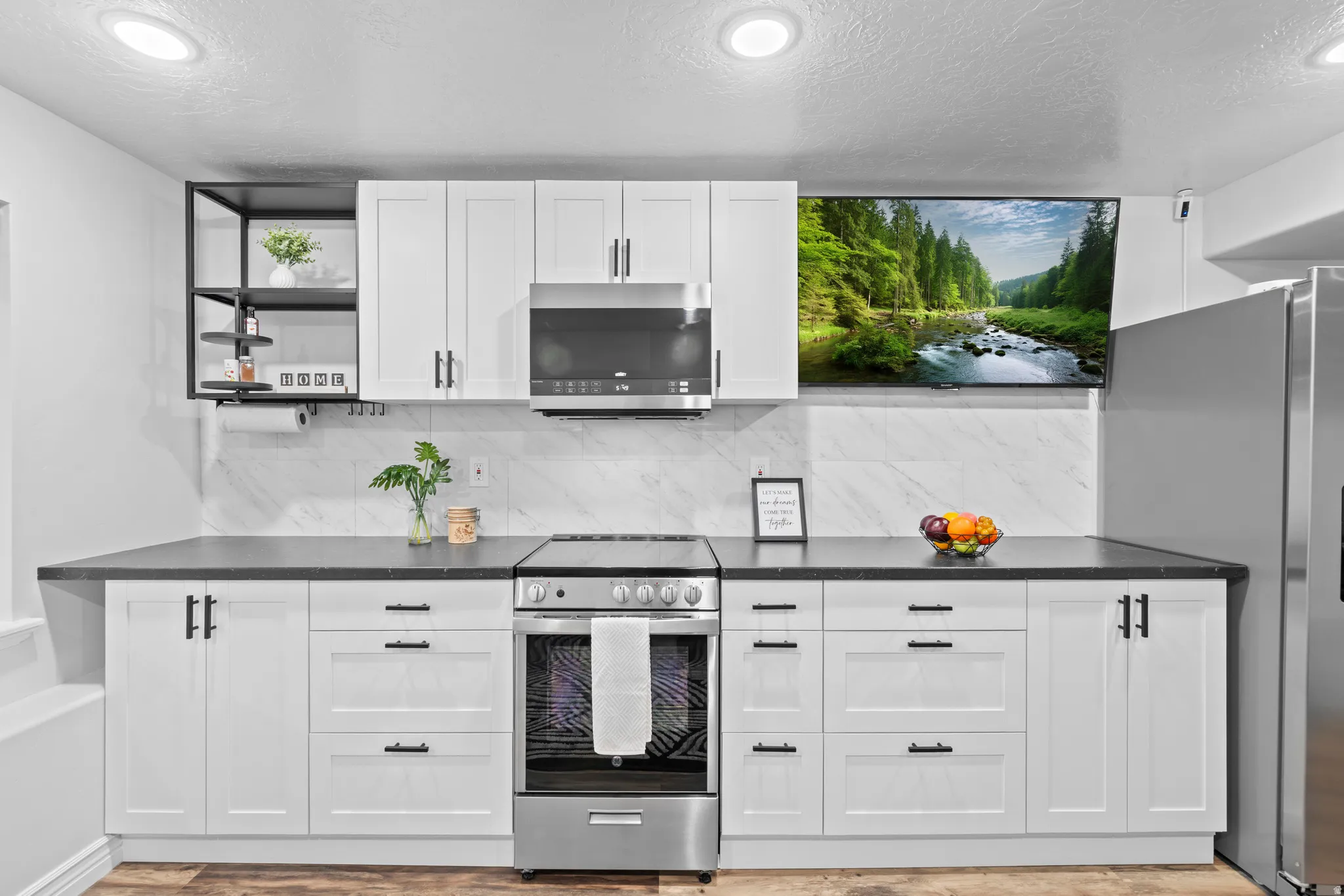 Modern kitchen featuring white shaker cabinetry, dark countertops, stainless steel appliances, a marble-look tile backsplash, and recessed lighting
