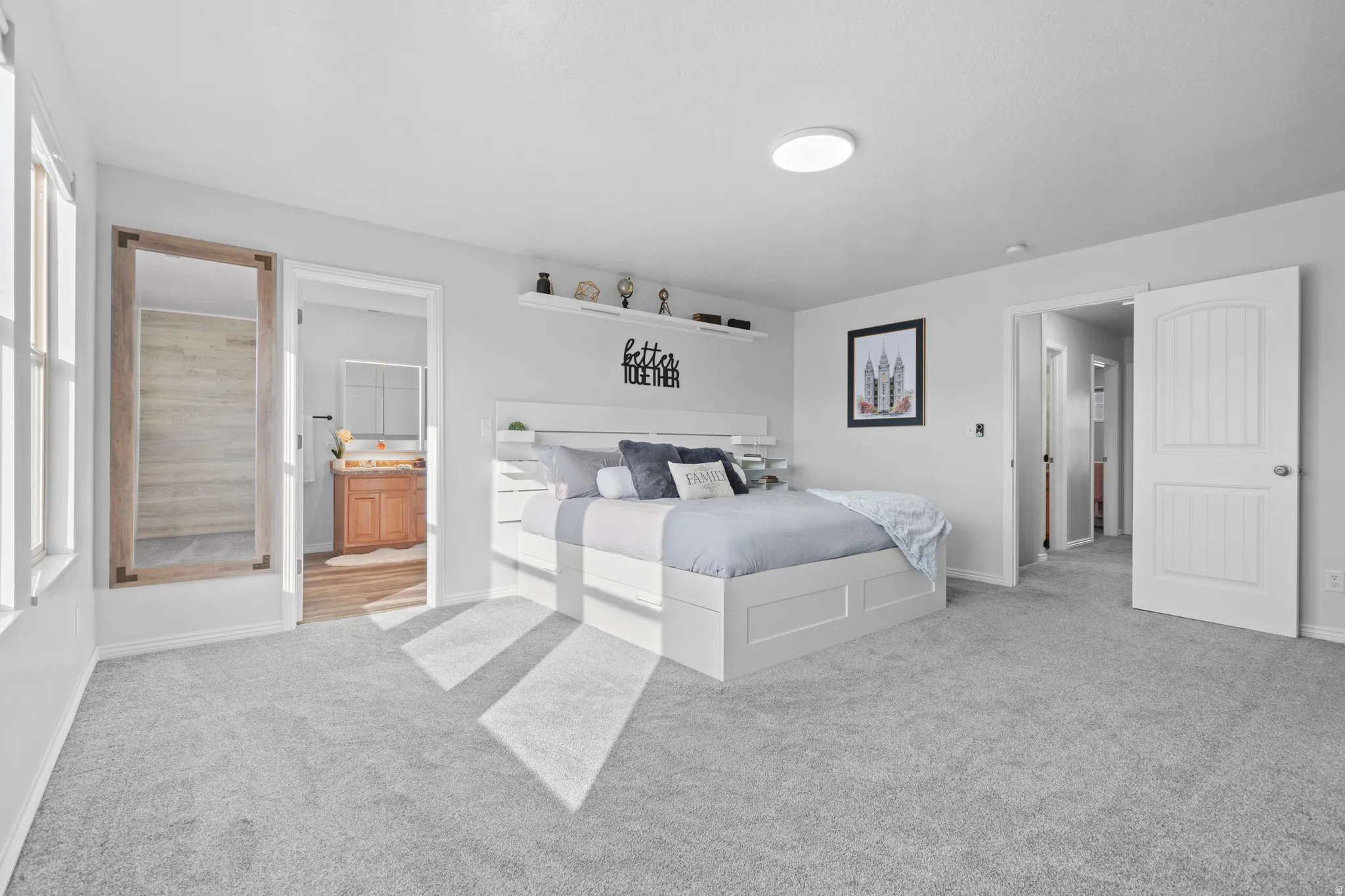 Carpeted room with light gray walls, featuring a built-in wall shelf, a white paneled door, and a recessed ceiling light fixture