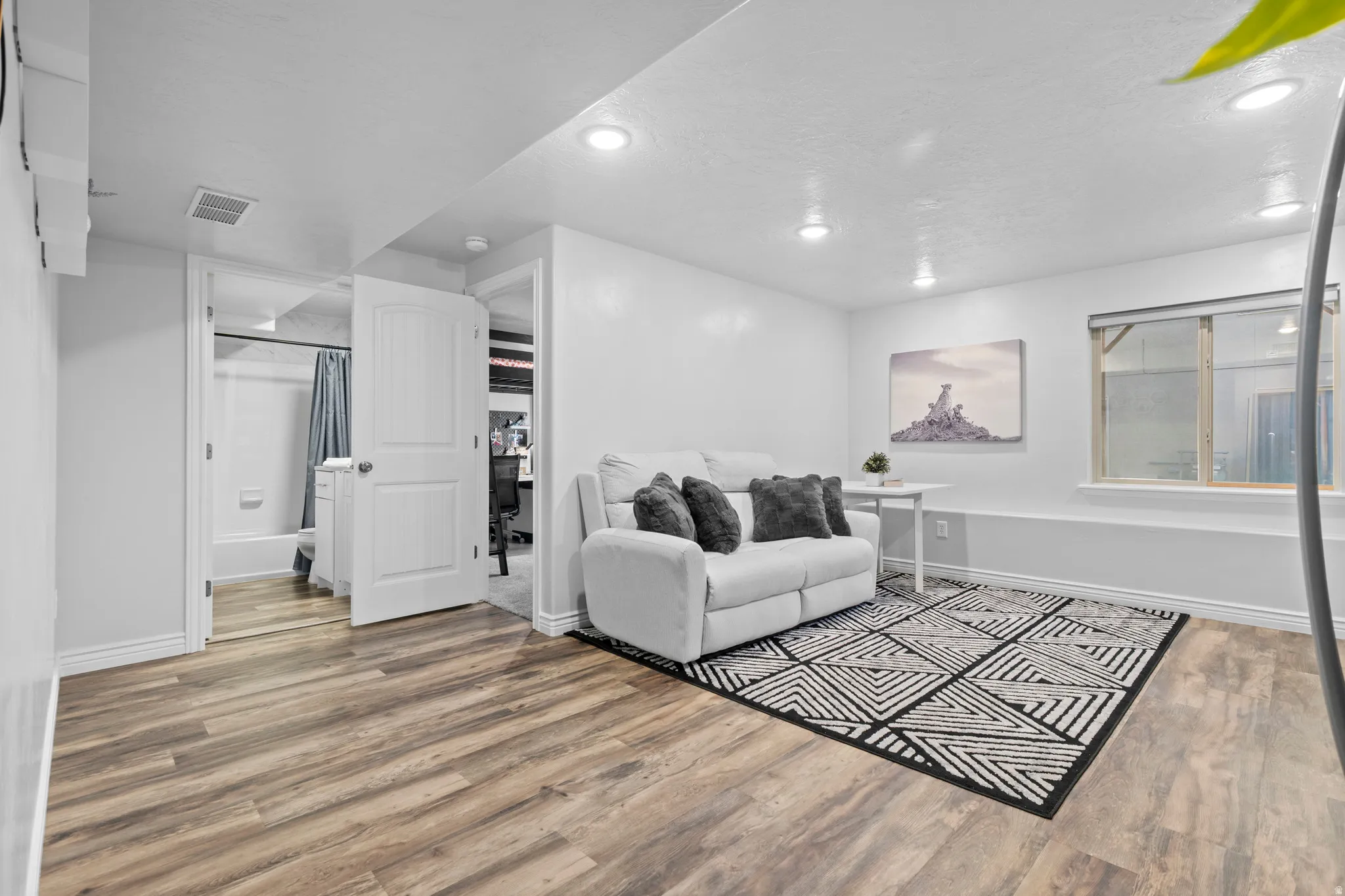 Spacious room featuring wood-finish flooring, recessed lighting, and a window