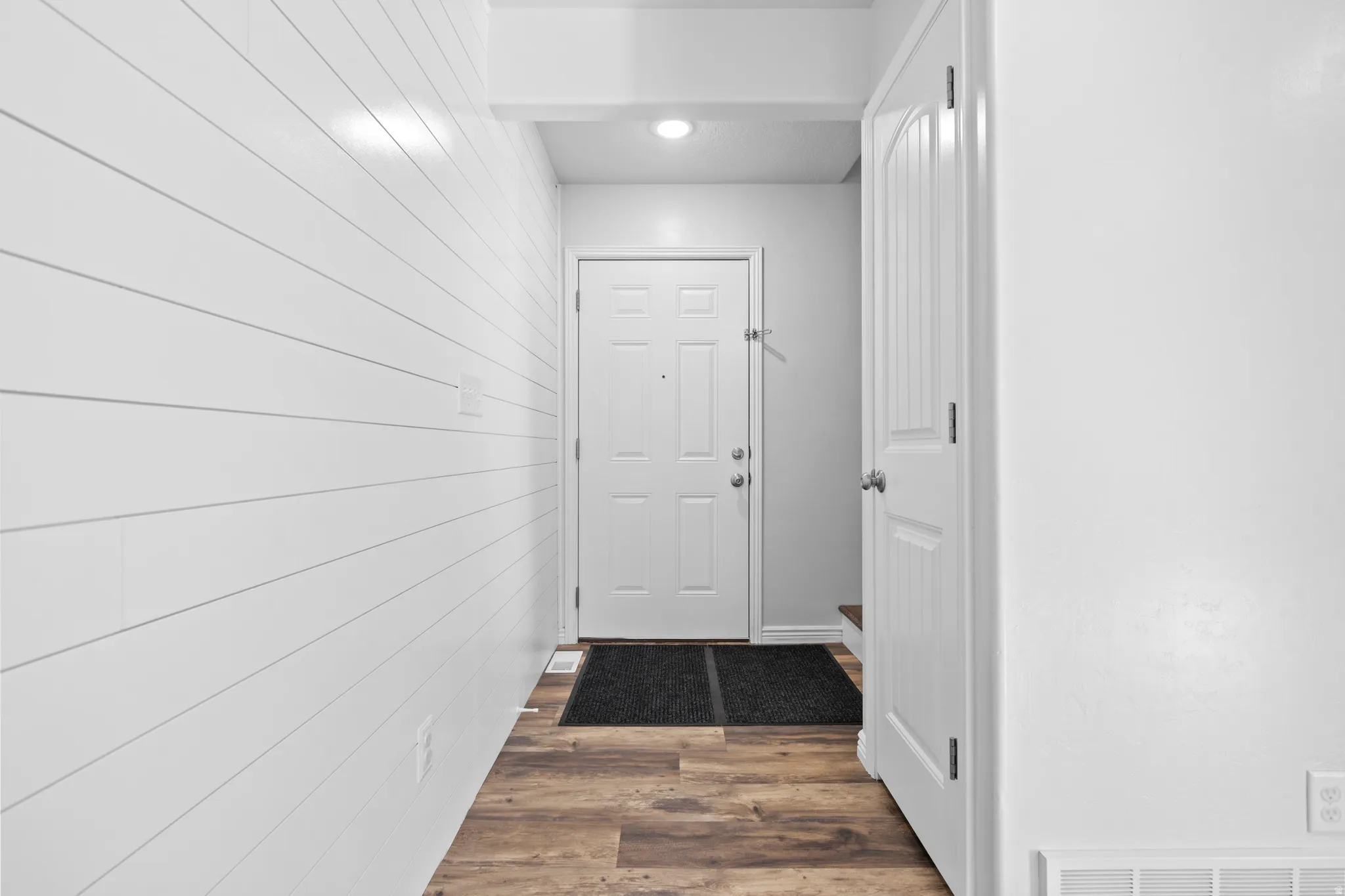 Entryway featuring wood-finish flooring, white shiplap wall paneling, and a flush-mount ceiling light