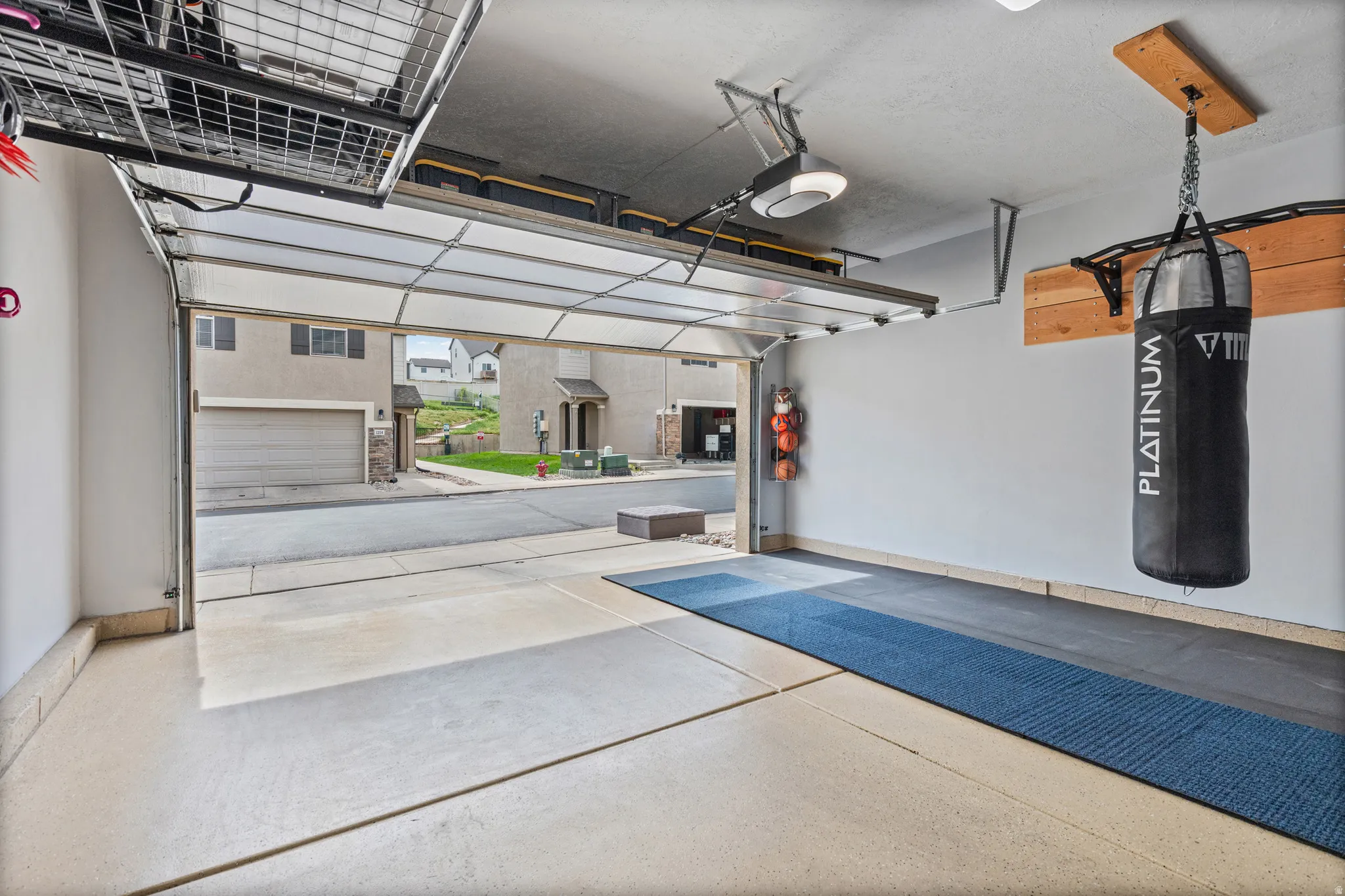 Garage featuring a clear-panel overhead door, overhead storage racks, an automatic garage door opener, and epoxy-coated flooring