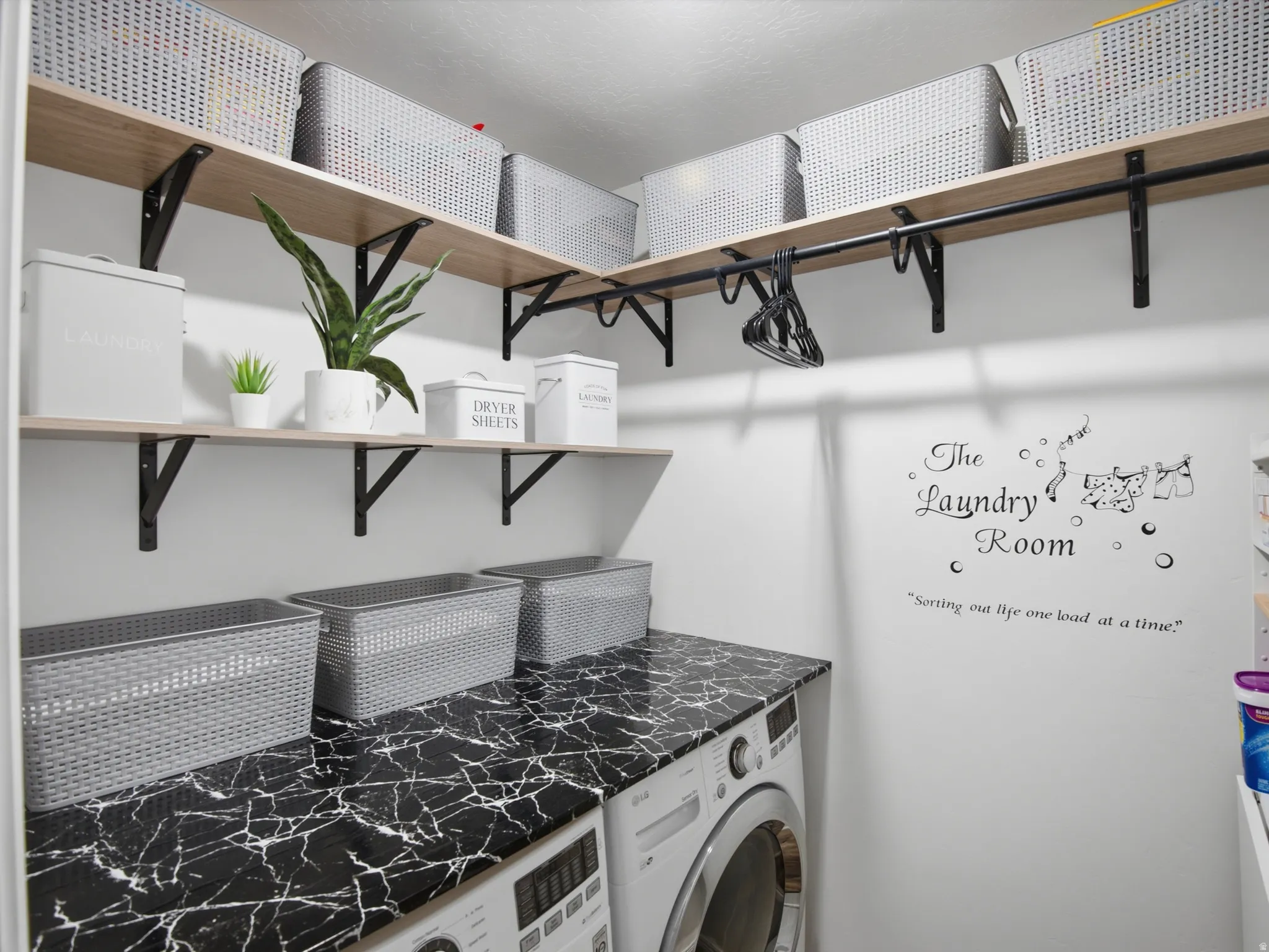 Dedicated laundry area featuring a patterned countertop, built-in shelving, and a clothing rod