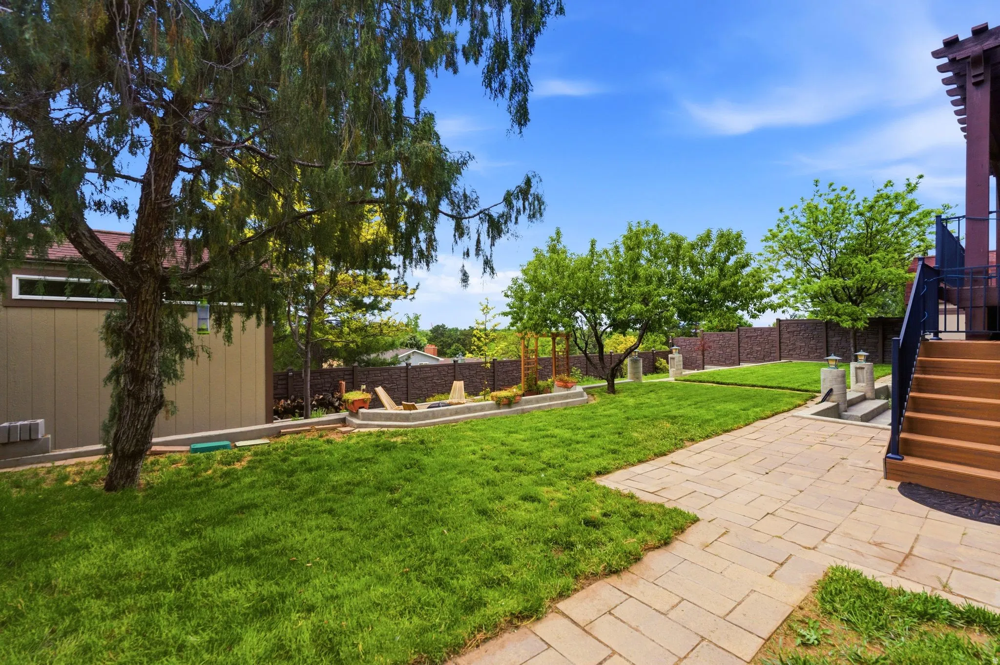 Expansive green lawn with a paver patio and mature trees