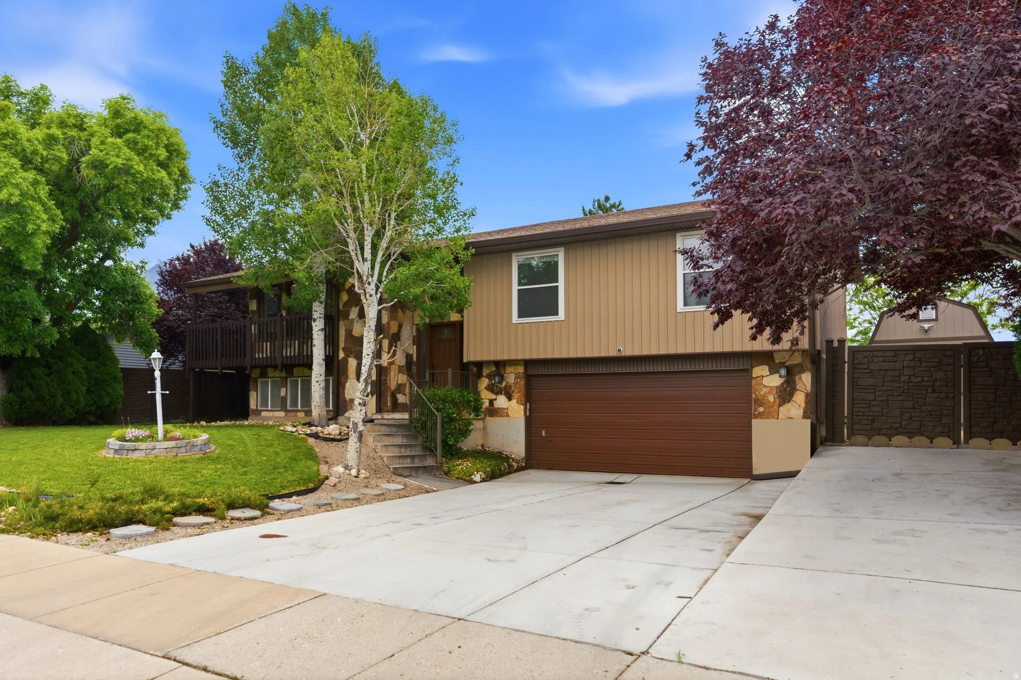 Split-level exterior featuring tan vertical siding and stone accents